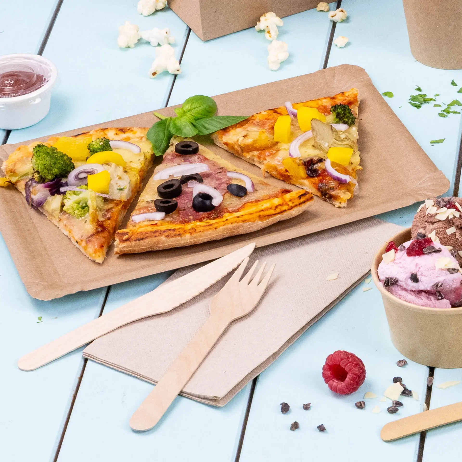Image of three slices of pizza with various toppings on a brown paper plate, accompanied by wooden utensils and a cup of ice cream.