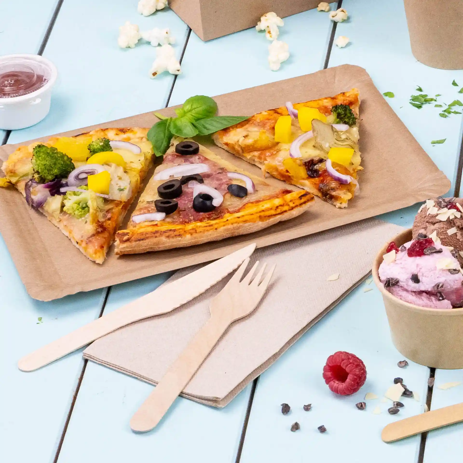 Image of three slices of pizza with various toppings on a brown paper plate, accompanied by wooden utensils and a cup of ice cream.