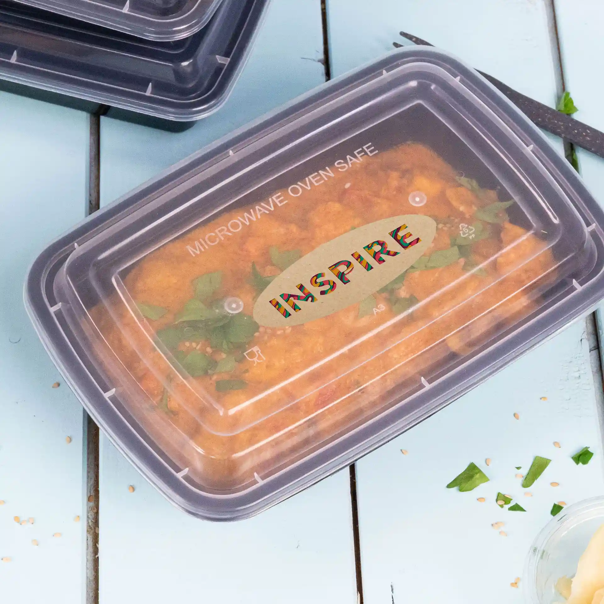 Container with a clear lid showing food inside, labeled with "MICROWAVE OVEN SAFE" and "INSPIRE" on top.