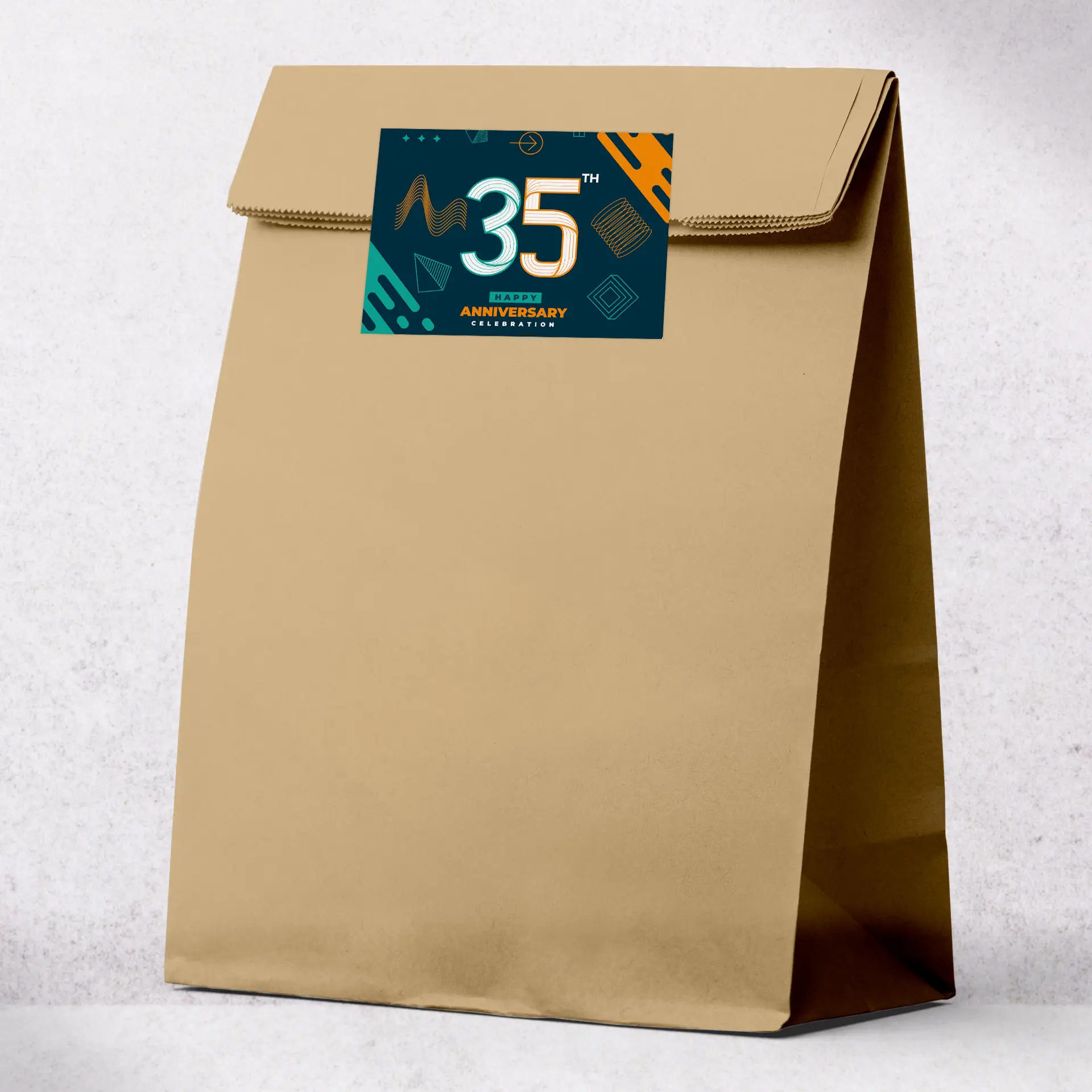 Brown kraft paper bag with a custom label featuring a 35th anniversary design, suitable for events and delivery services.