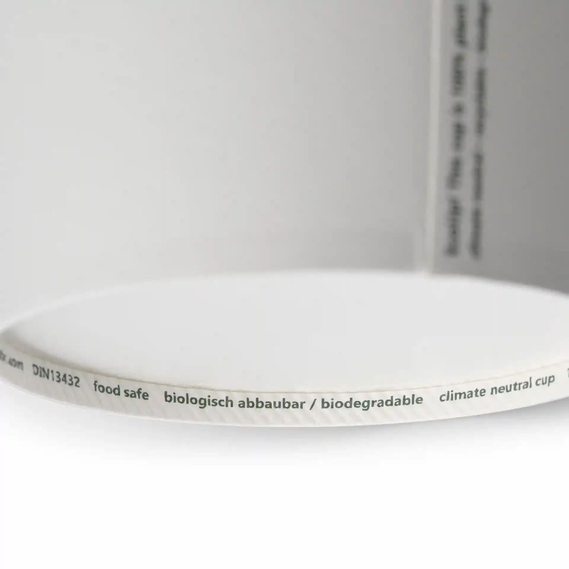 Close-up of the rim of a white cardboard soup container showing a label with markings and a smooth interior surface.