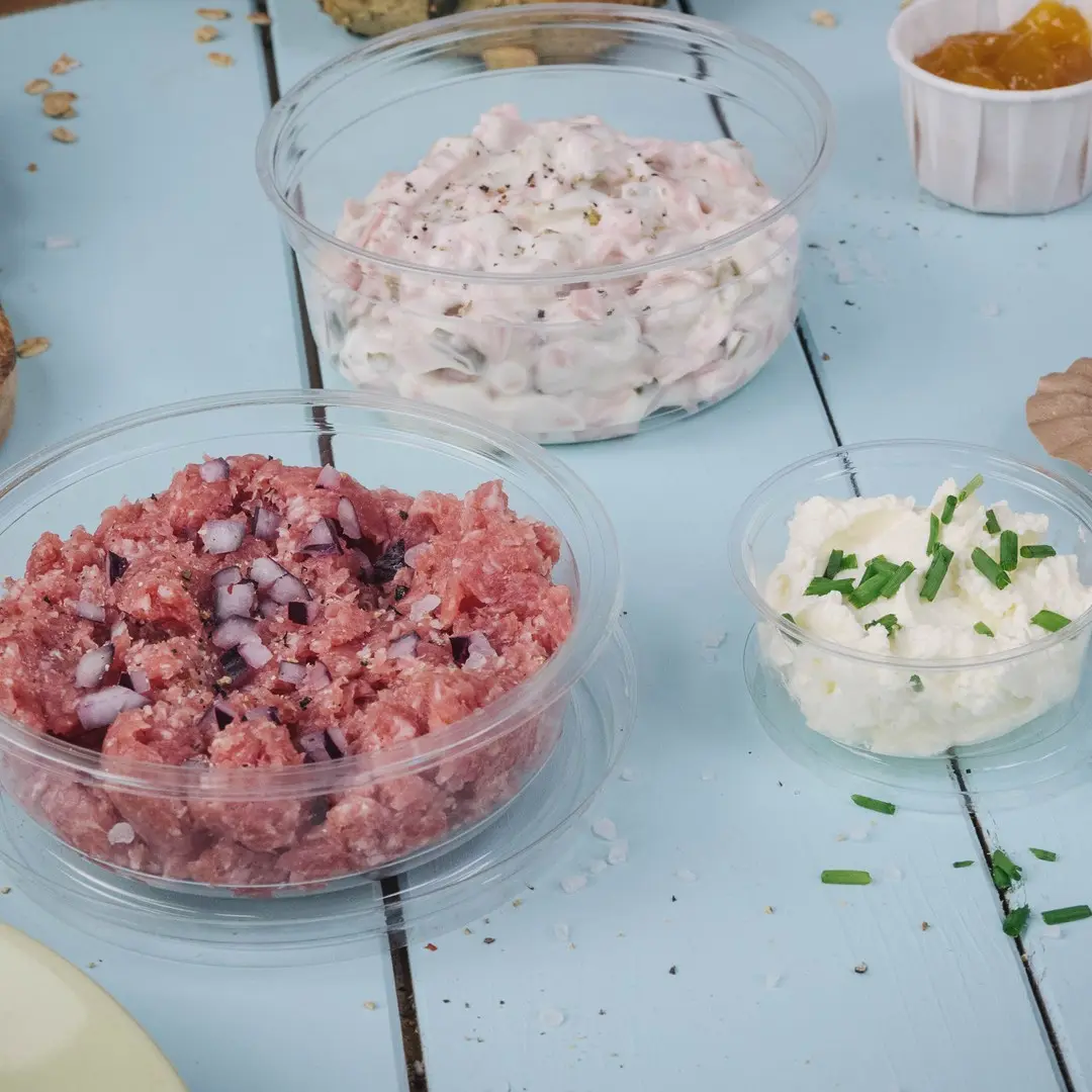 Three transparent containers with different spreads: pink meat mixture with onions, creamy white spread, and a white cheese spread topped with chives.