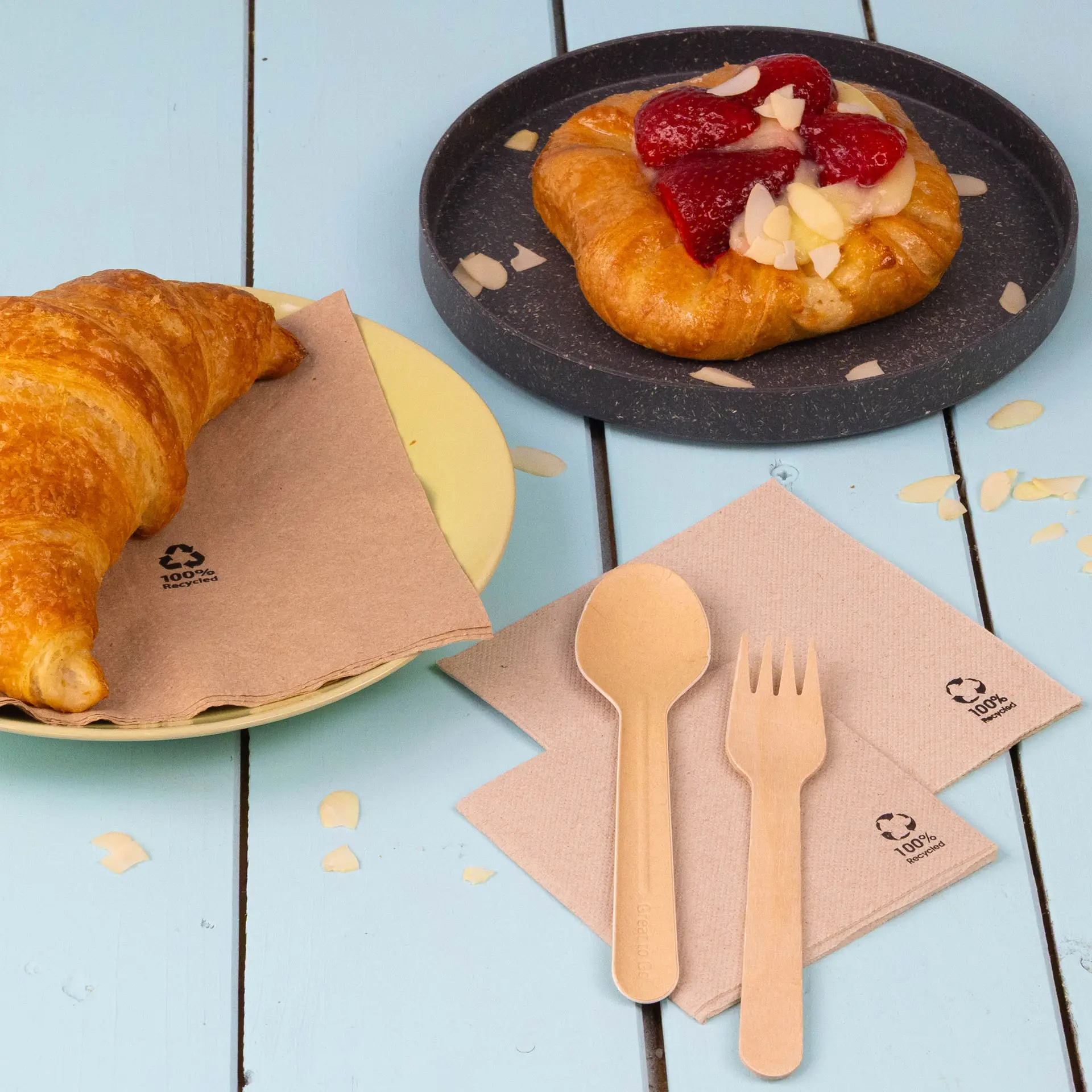 One coffee cup on a white plate with a cookie, surrounded by a cup of raspberries and granola, and paper napkins.