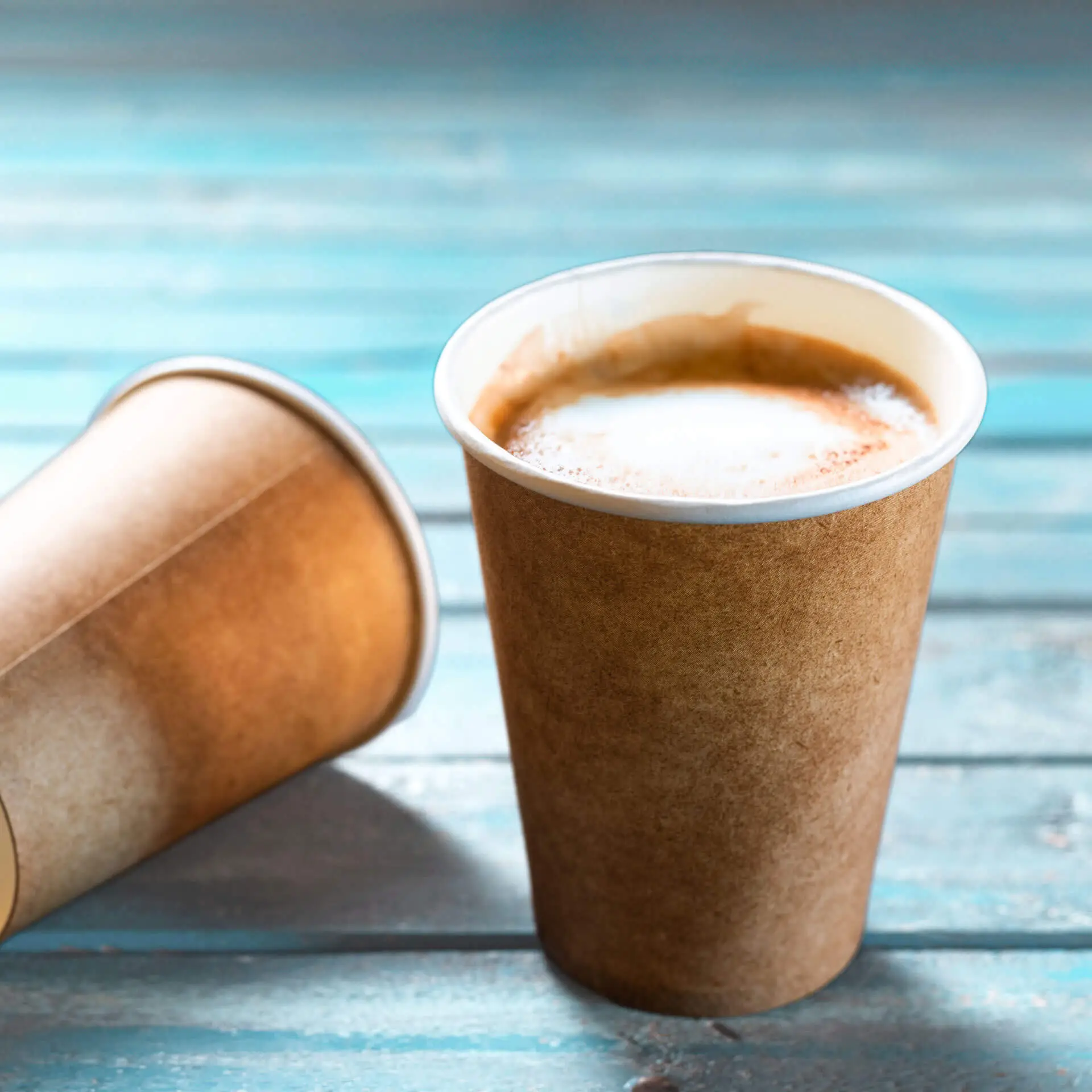 Brown paper cup with a white inner lining, 300 ml capacity, placed on a blue wooden surface.