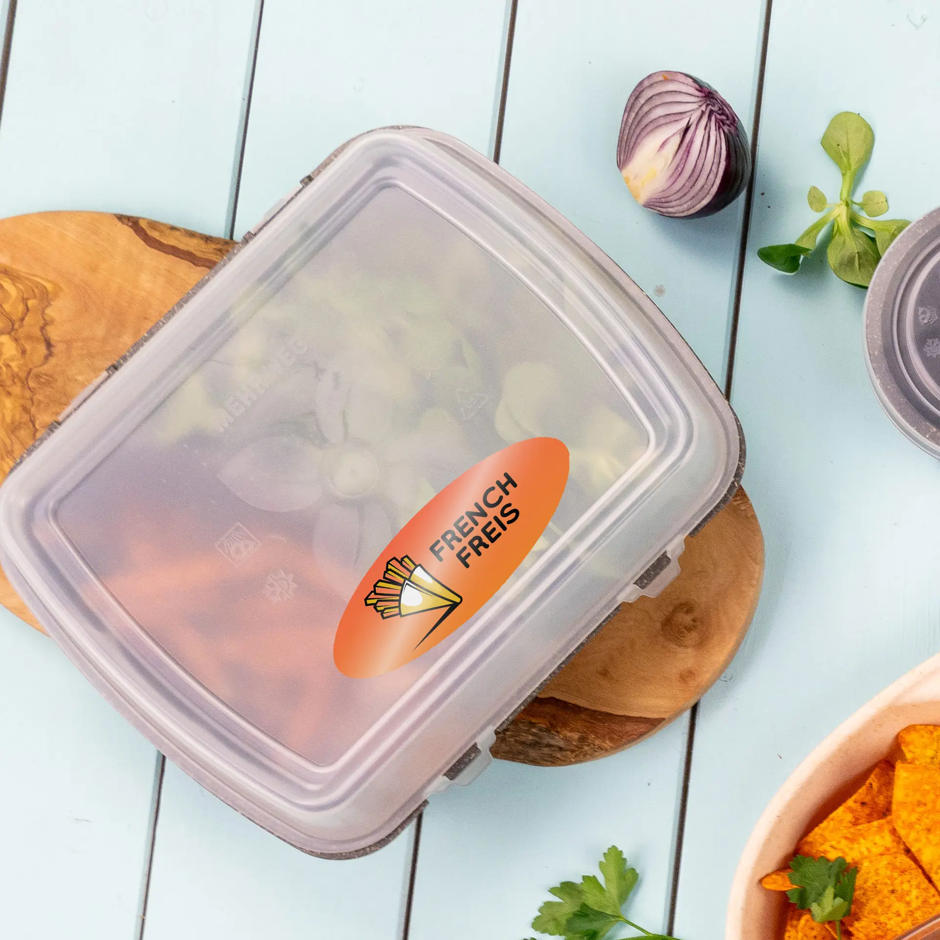 Clear oval label with "FRENCH FRIES" text on a container, surrounded by fresh ingredients on a wooden board.