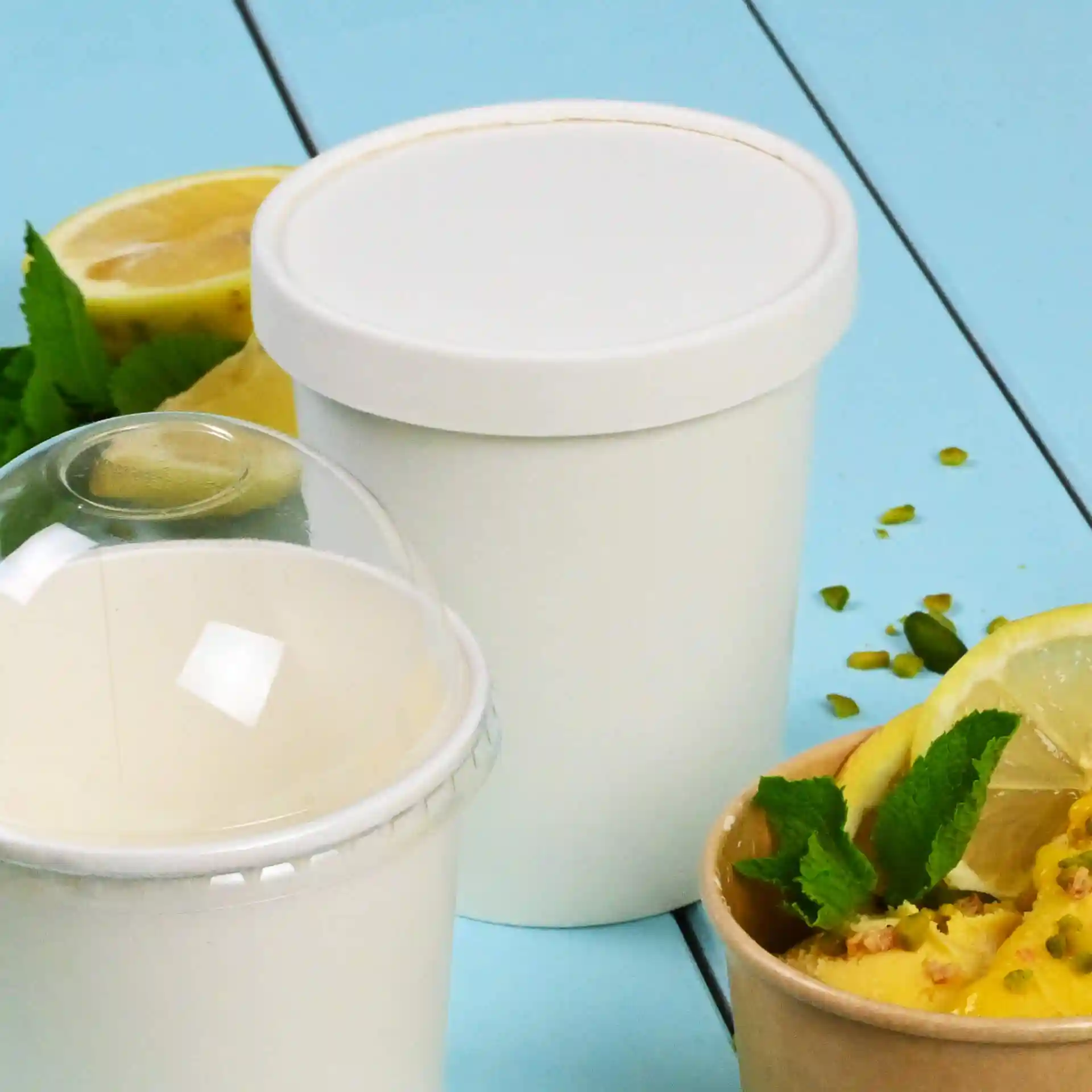 White round paper lid for ice cream tubs, placed next to a white tub and garnished with lemon slices and mint leaves.