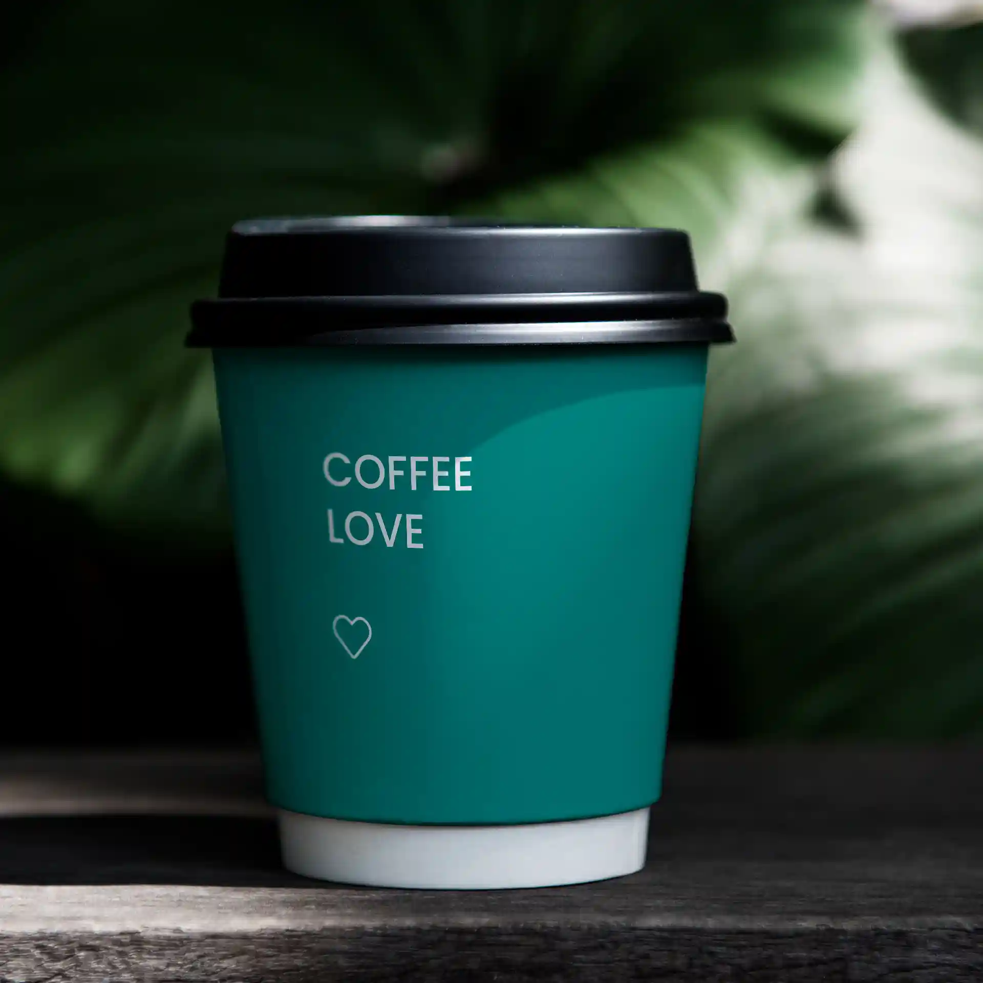 Teal paper coffee cup with a black lid, featuring the text "COFFEE LOVE" and a heart symbol.