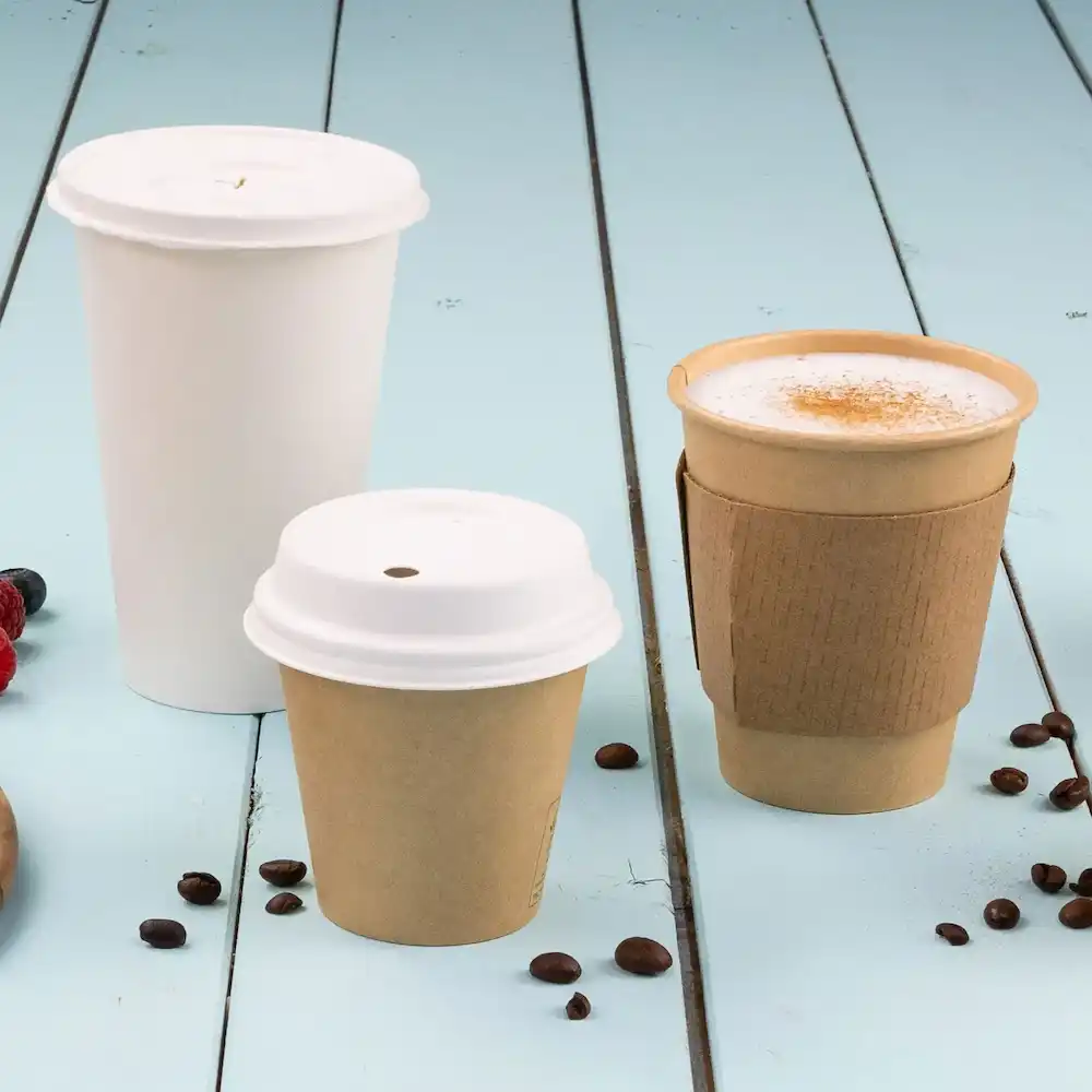 Three disposable paper cups in varying sizes: one large white cup, a medium brown cup, and a small brown cup with a sleeve.