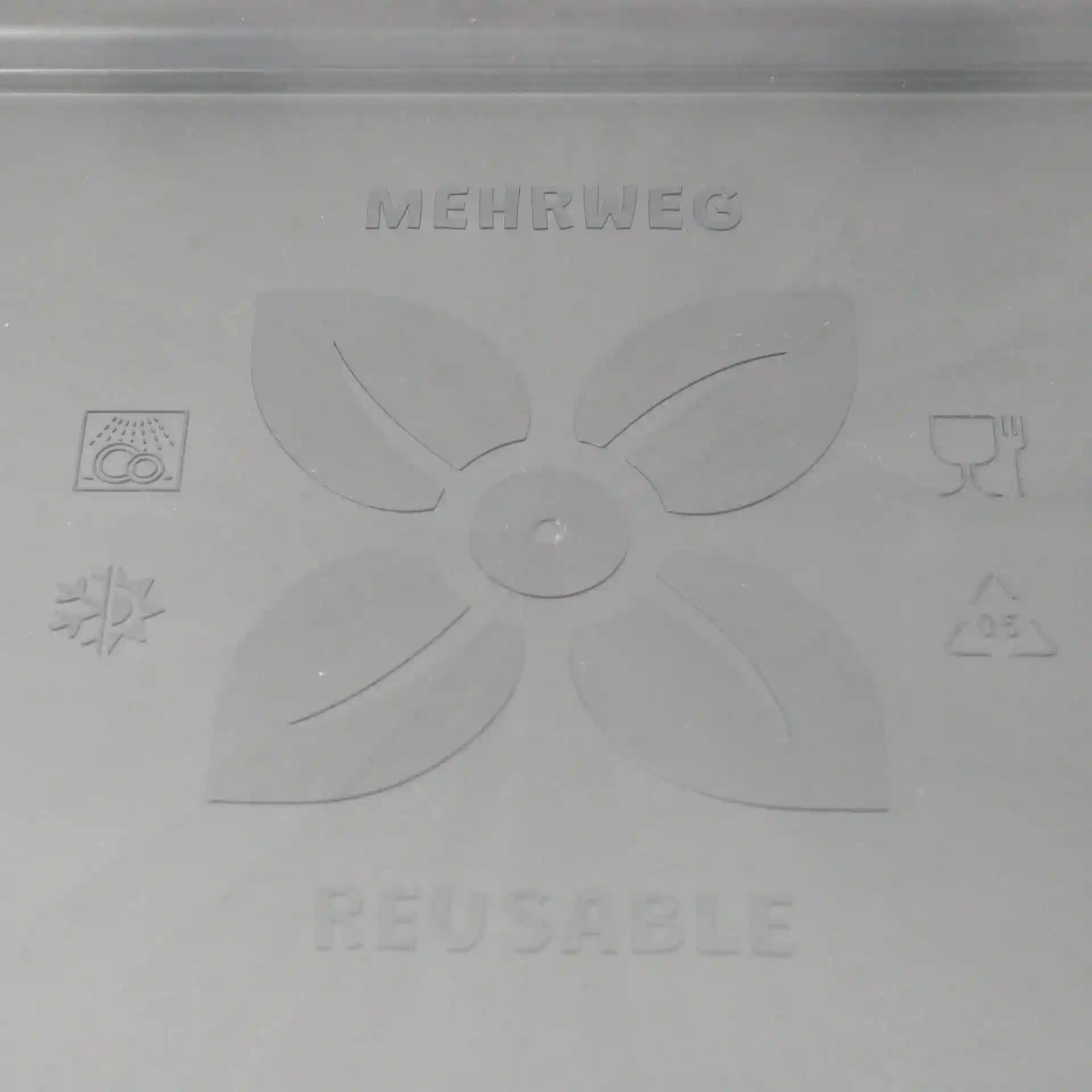 Schematic drawing of a grey reusable lid with leaf design and various symbols on a plain background.