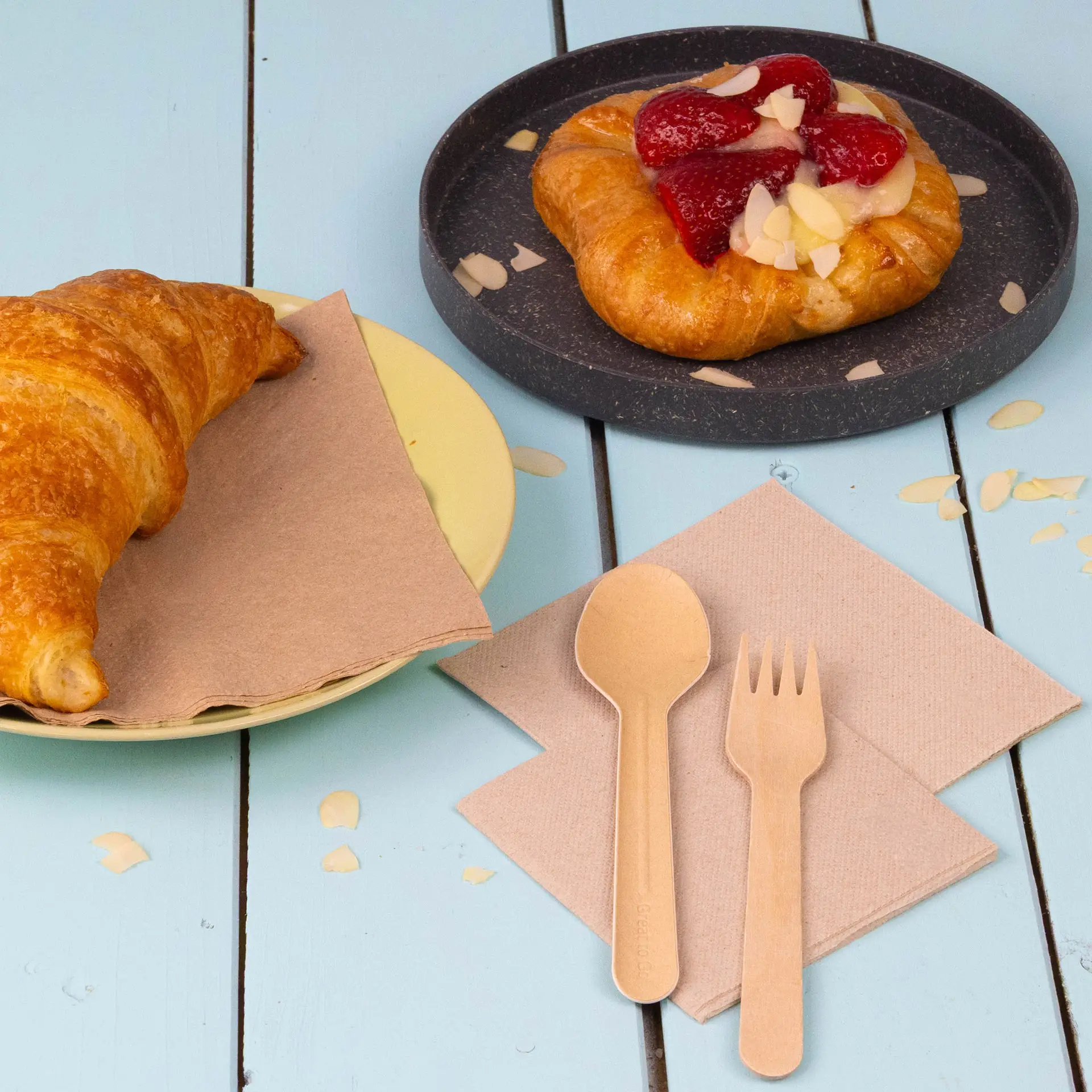 Square unbleached napkin on a wooden surface with a pretzel beside it.