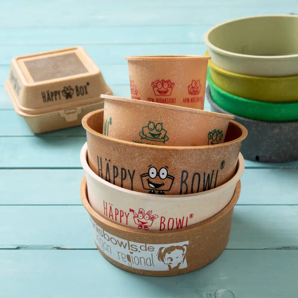 Several different bowls and a takeout container with various colorful designs on a wooden surface.