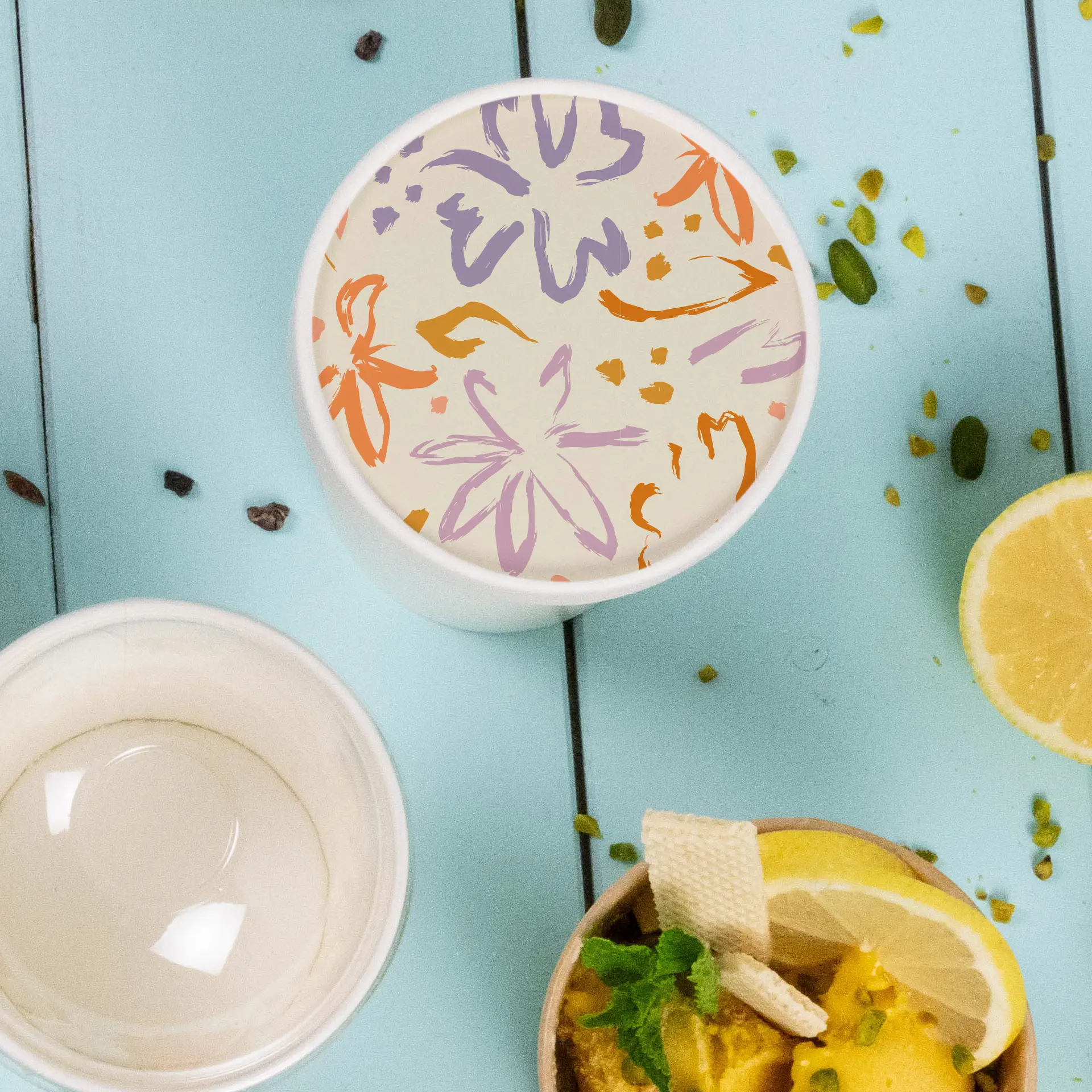 Printed cardboard lid for ice cream cups with a floral design in orange, purple, and yellow on a light background.