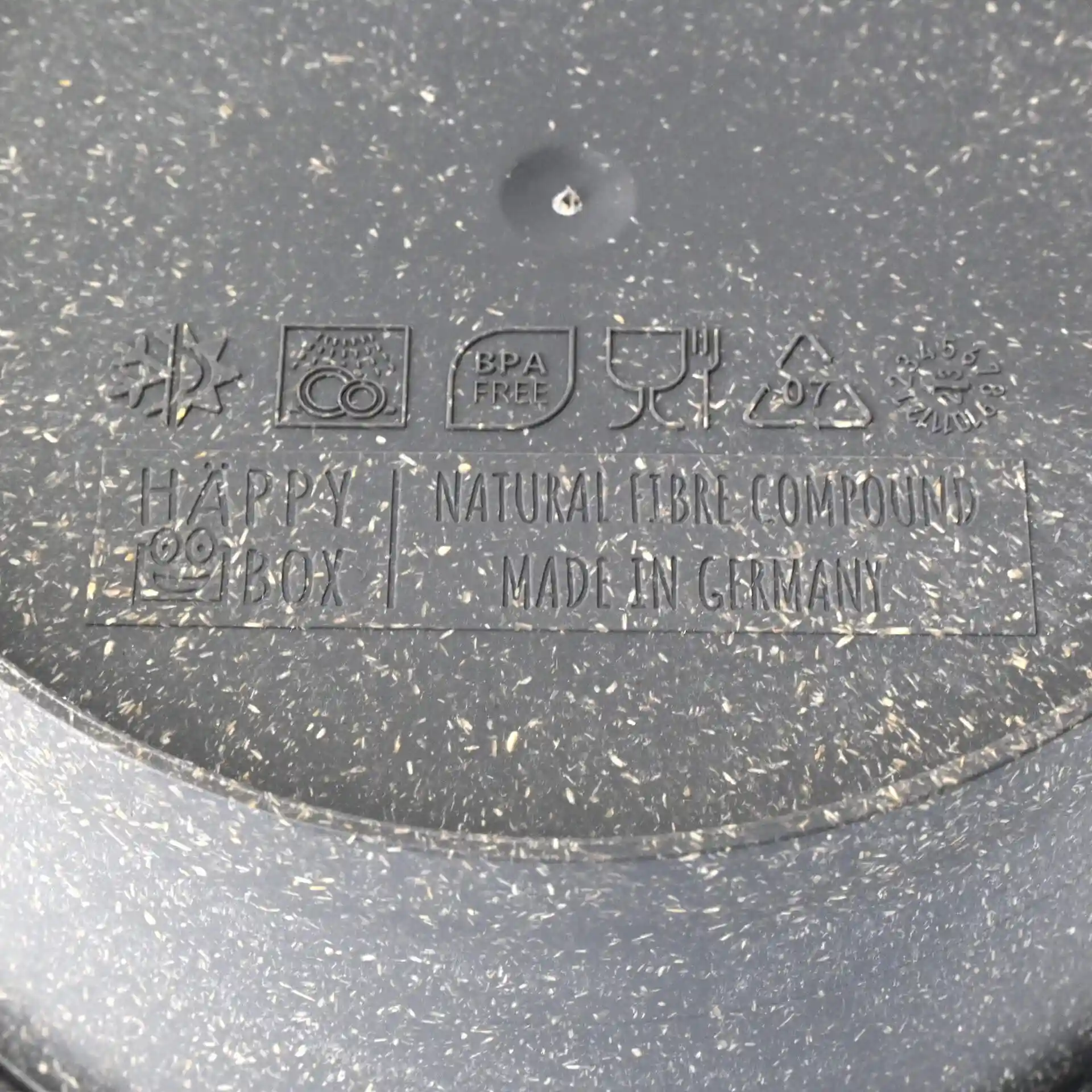 Label with symbols and text on the bottom of a grey reusable bowl made from natural fibre compound.