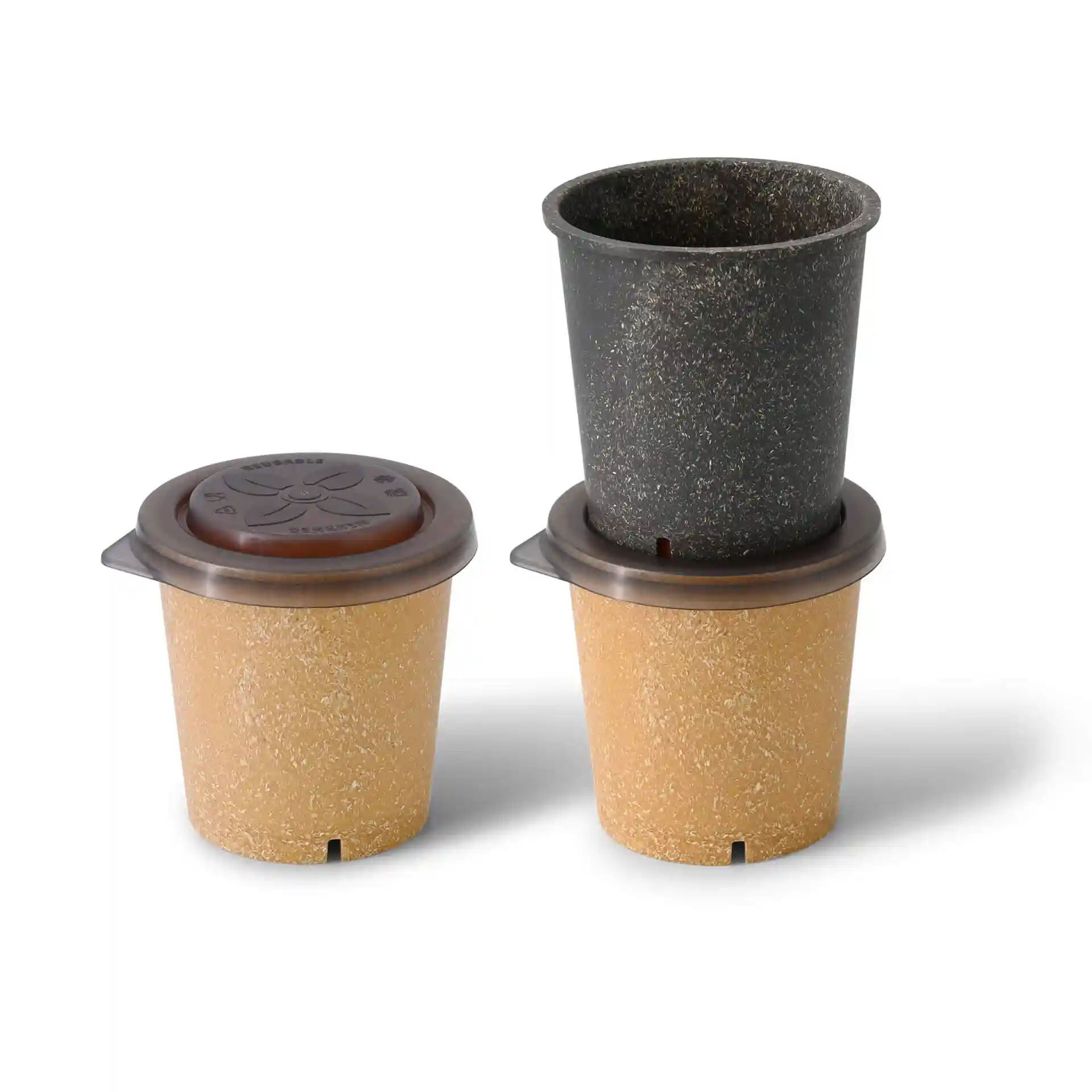 Three reusable cups in beige and black, with a brown lid on the top cup, arranged on a plain background.