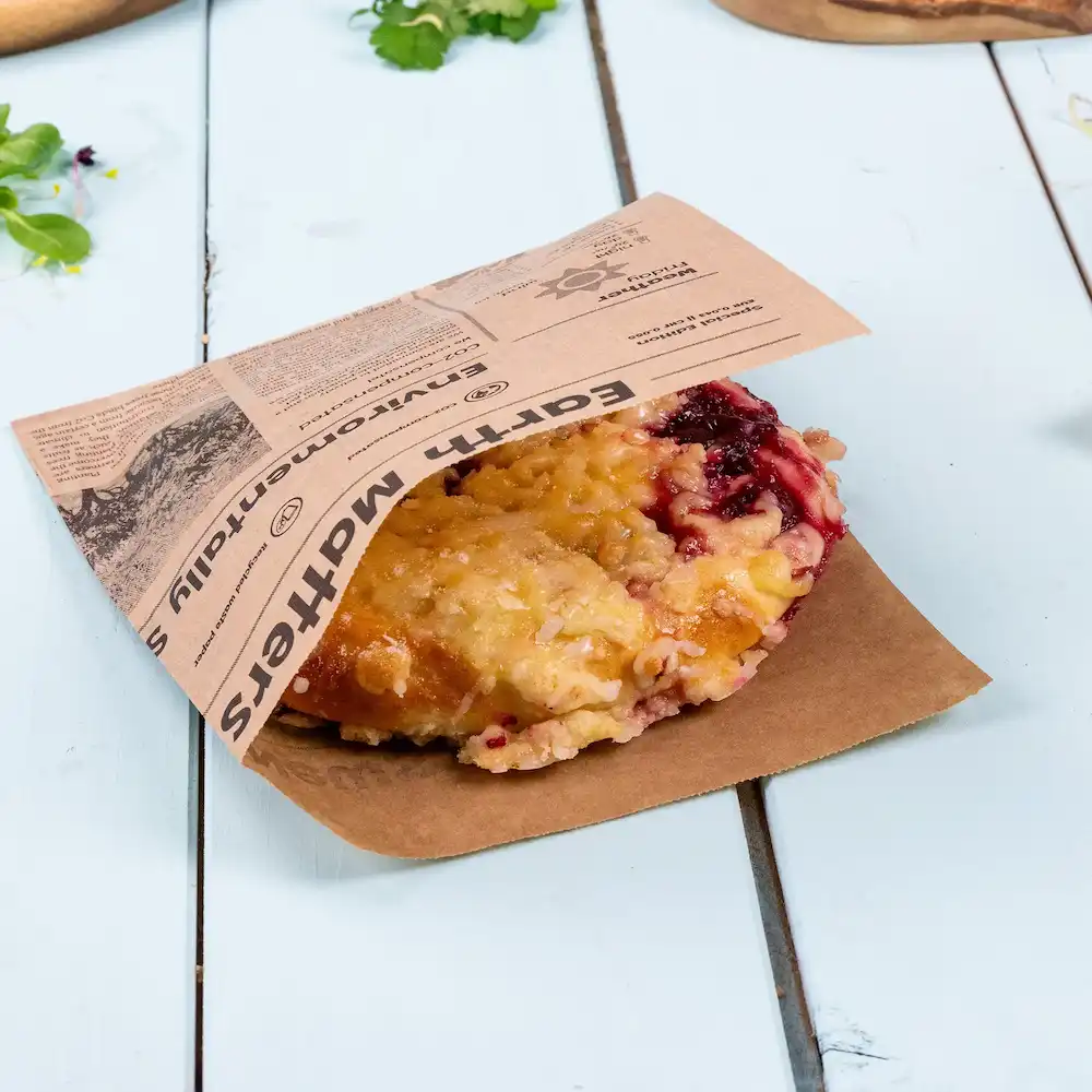 A baked item with a fruit filling, partially wrapped in a brown paper bag with a printed label.