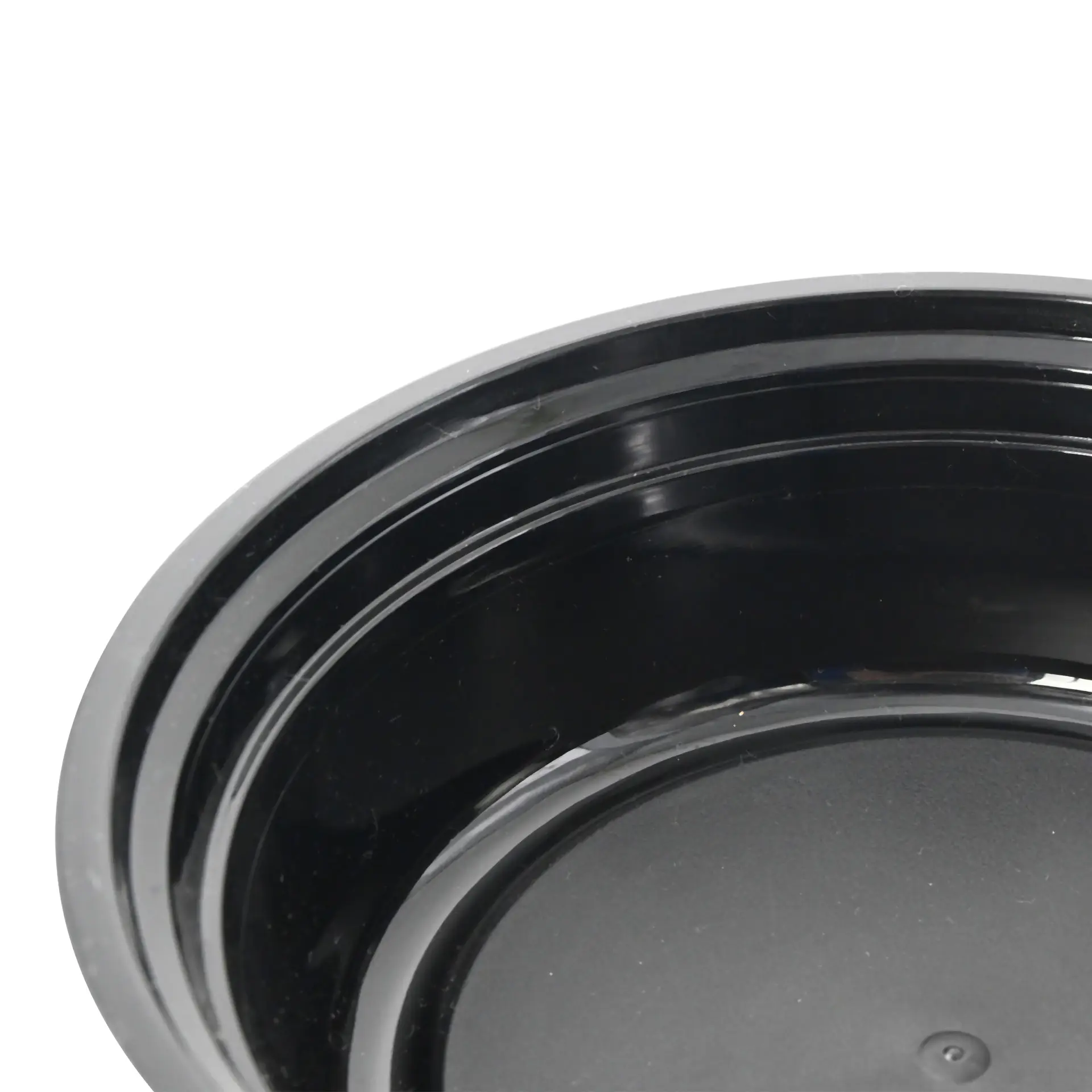 One round black reusable plate made of polypropylene, featuring a smooth surface, designed for hot and cold dishes.