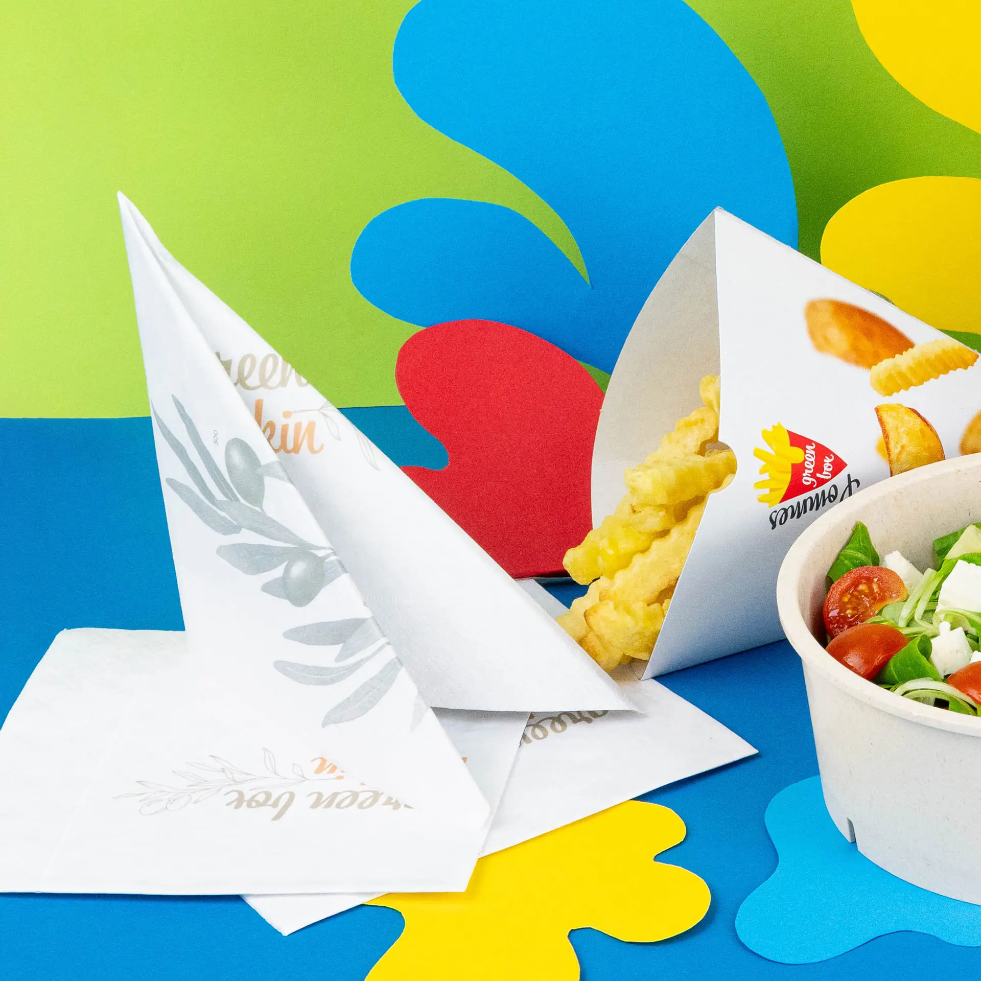 Image of printed napkins in a quarter fold, with crinkle fries and a salad bowl on a colorful background.