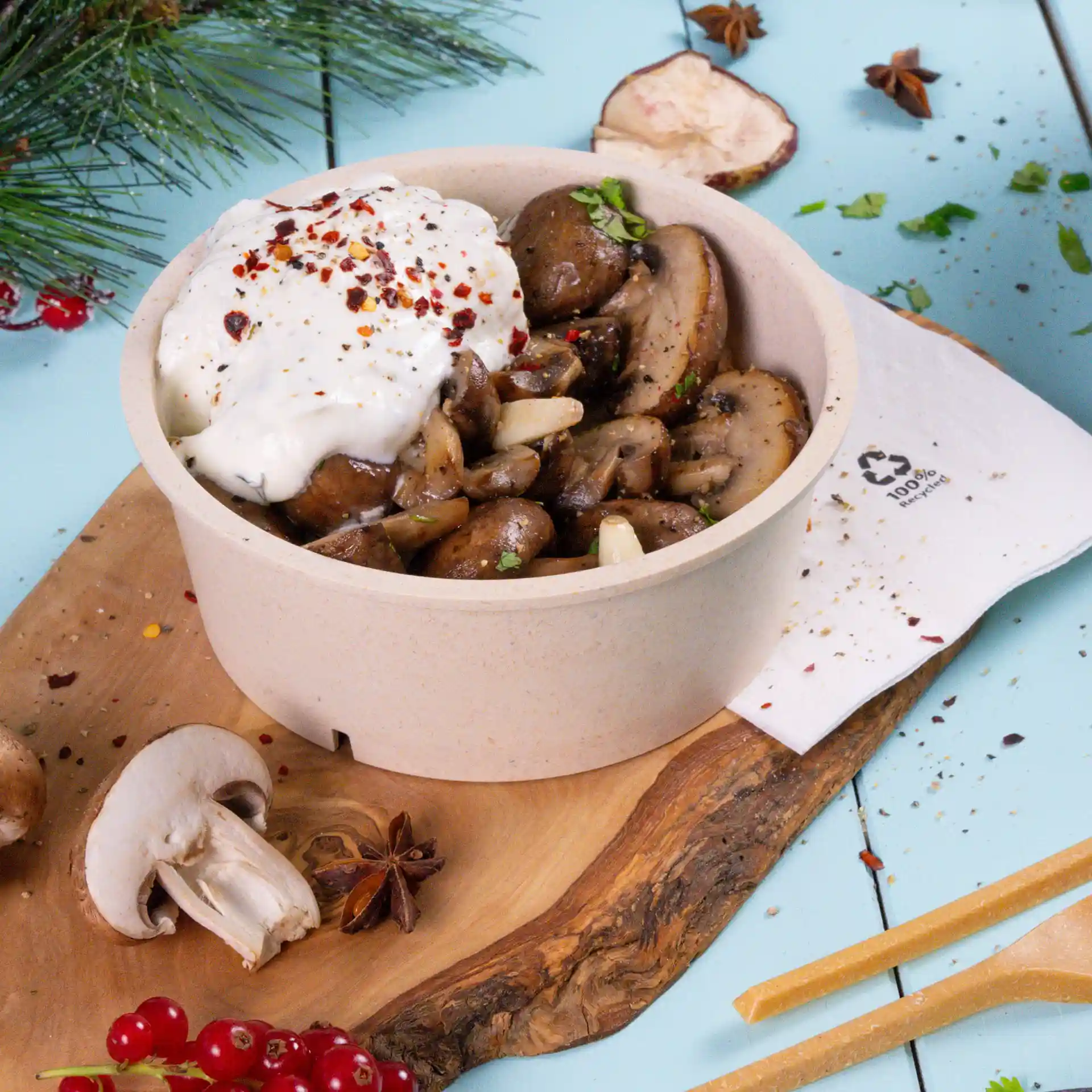 Round cream white reusable bowl filled with sautéed mushrooms and topped with a dollop of cream and spices.