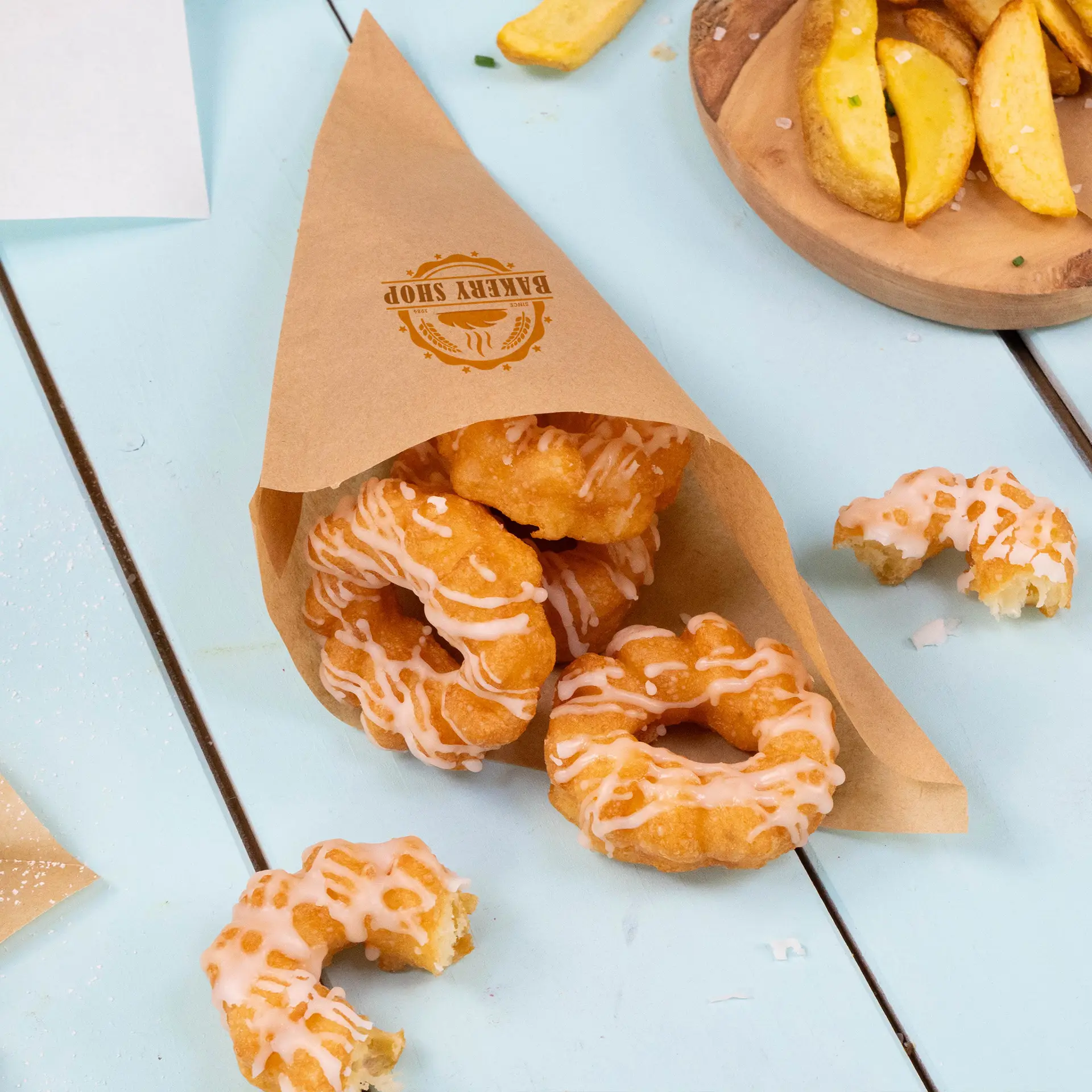 Brown paper cone bag containing glazed donuts, with a logo visible on the side, placed on a blue surface.