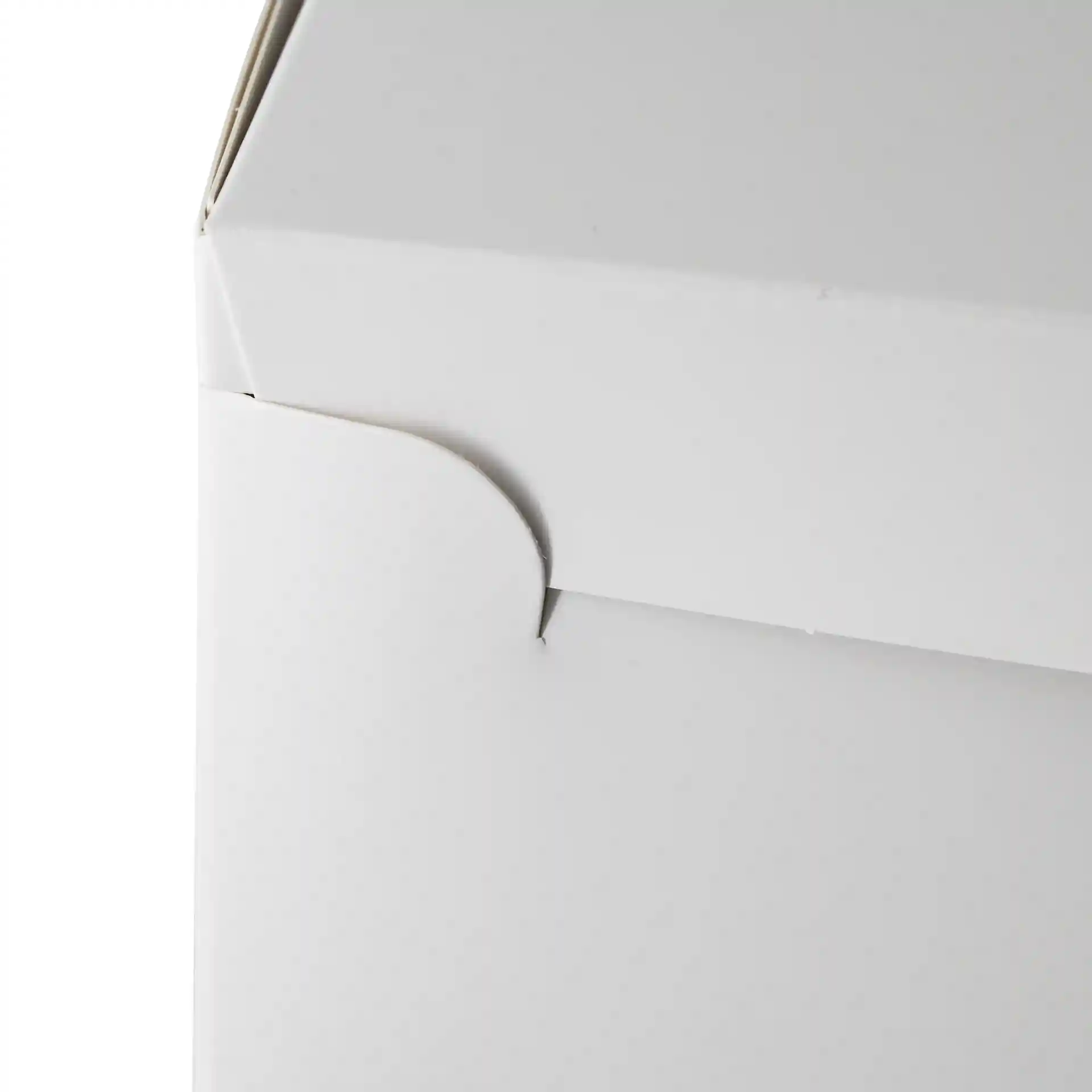 Close-up of a white cake box with a curved flap on the side.