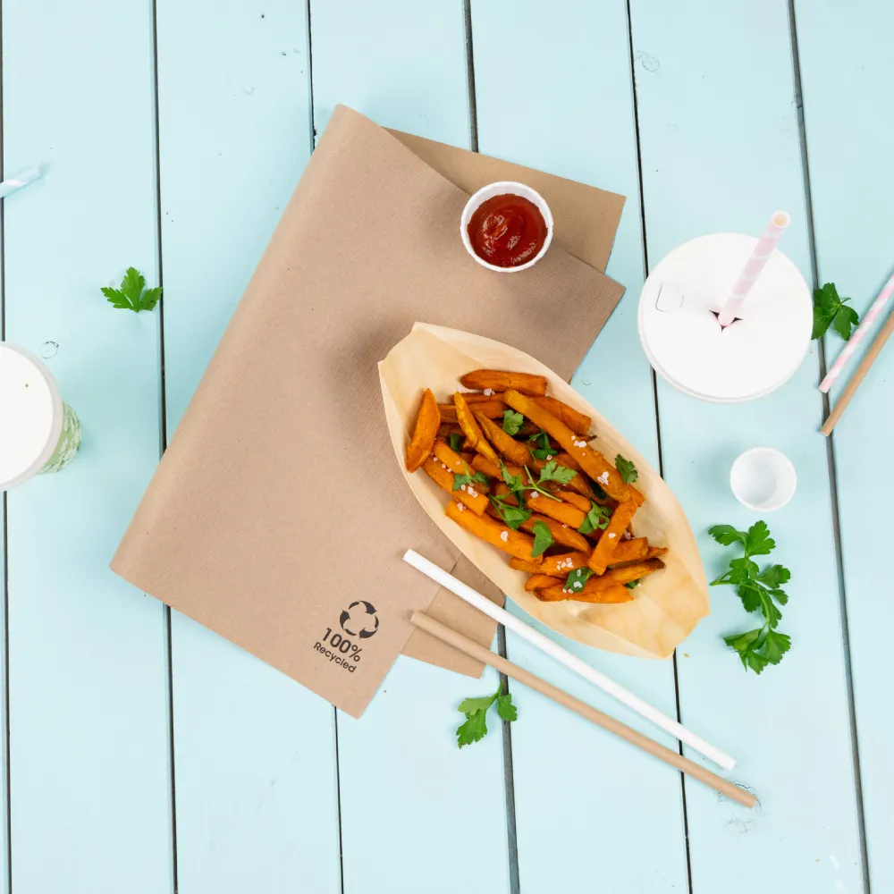 Brown paper table cover labeled "100% Recycled" with sweet potato fries garnished with herbs, ketchup, and drinks.