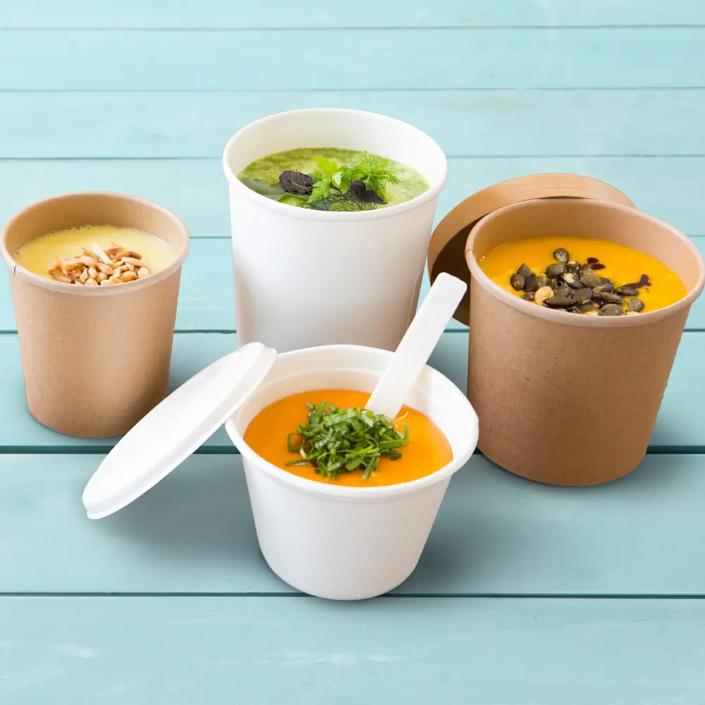 Assorted soup containers on a blue surface; includes two white and two brown cups with various toppings.