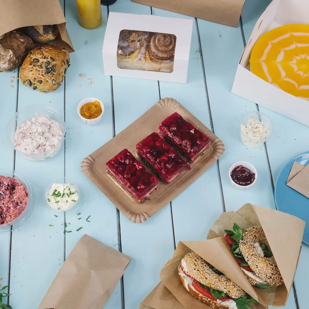 Assorted baked goods and desserts on a blue table, including jelly cakes, sandwiches, and dips in containers.