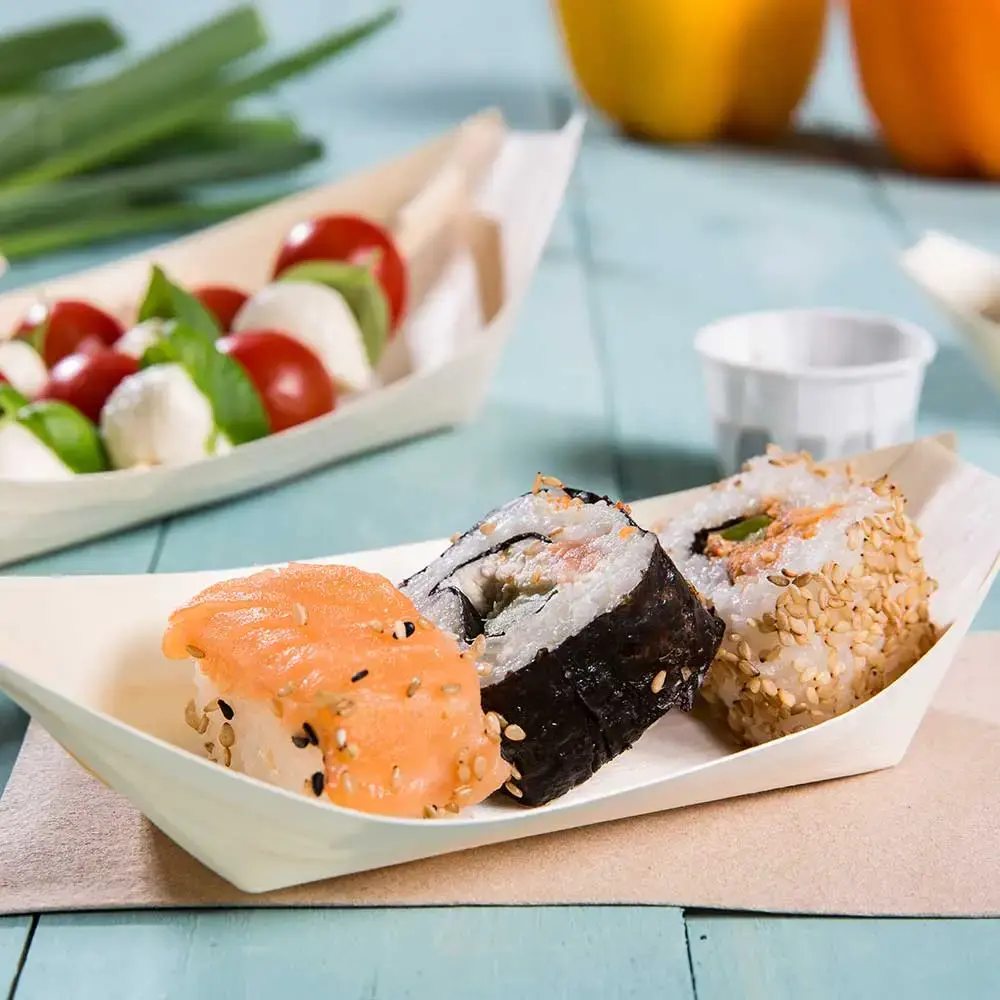 Sushi rolls served in a wooden boat-shaped dish, featuring salmon, sesame, and nori, with a side of cherry tomatoes and mozzarella.