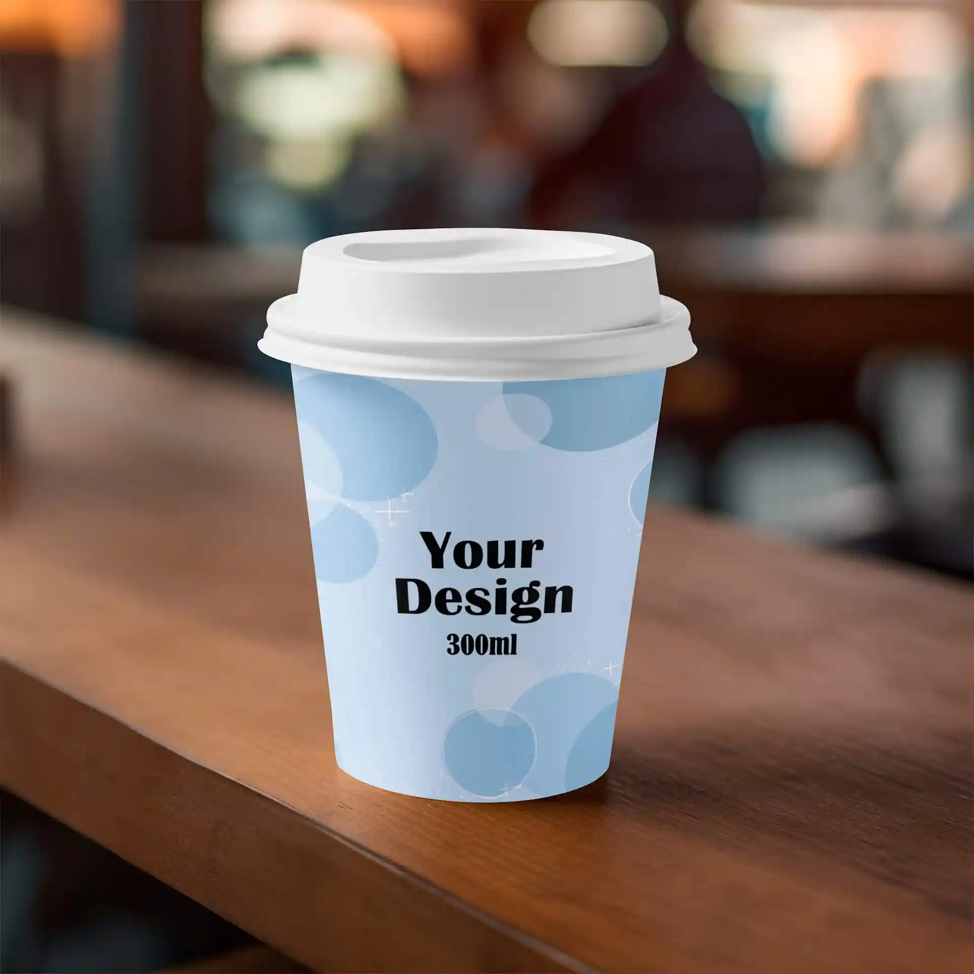 Paper cup with a white lid, featuring a light blue design and black text, placed on a wooden surface.
