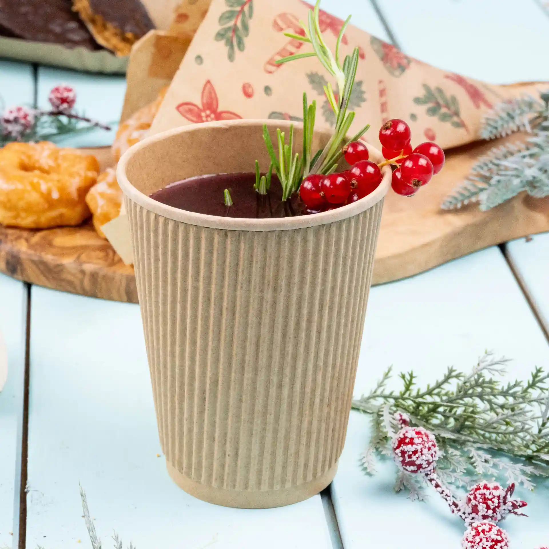 Ribbed kraft paper cup filled with yellow liquid, placed near a lemon half and blueberries on a blue wooden surface.