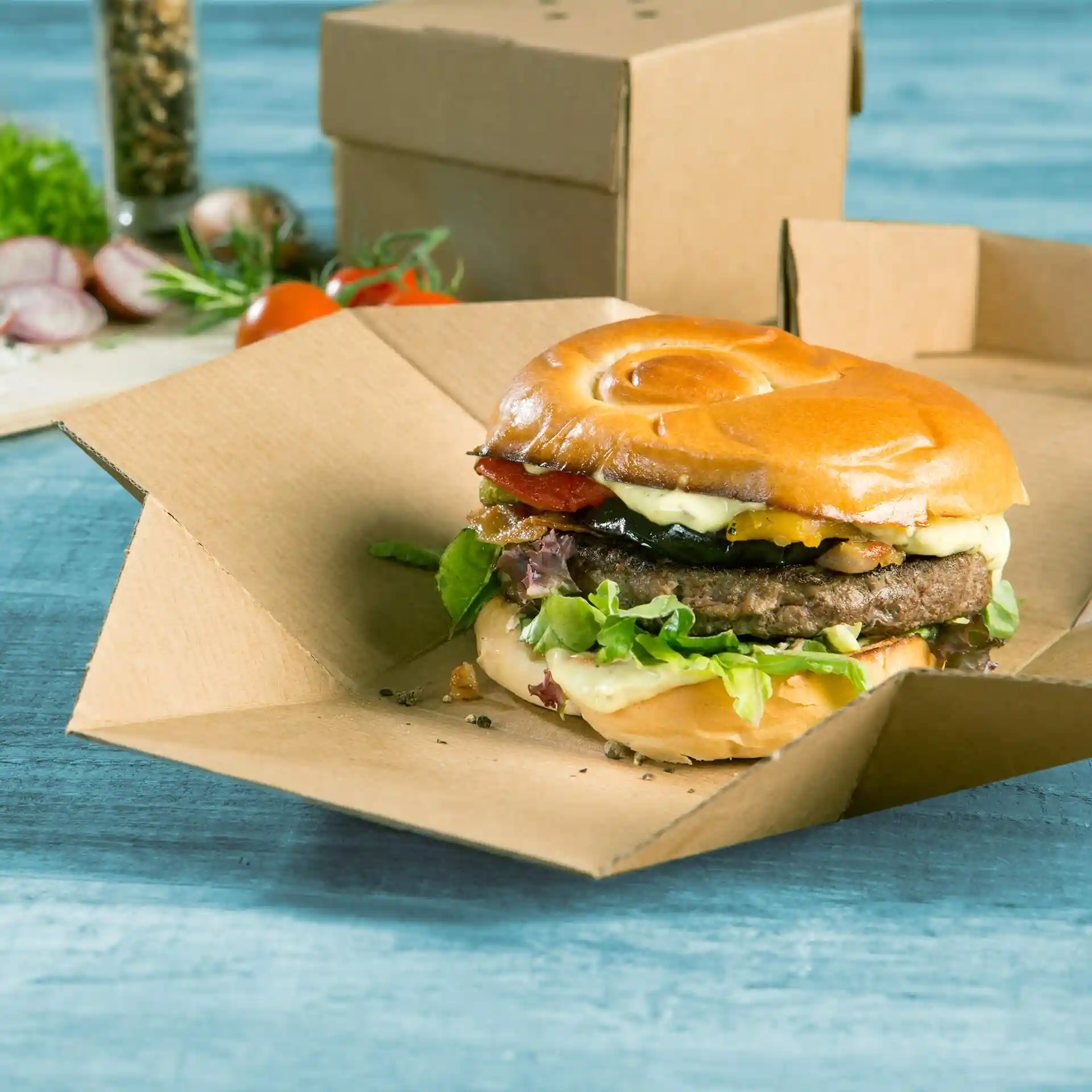 Burger in a foldable brown cardboard box, featuring lettuce, cheese, bacon, and a soft bun.