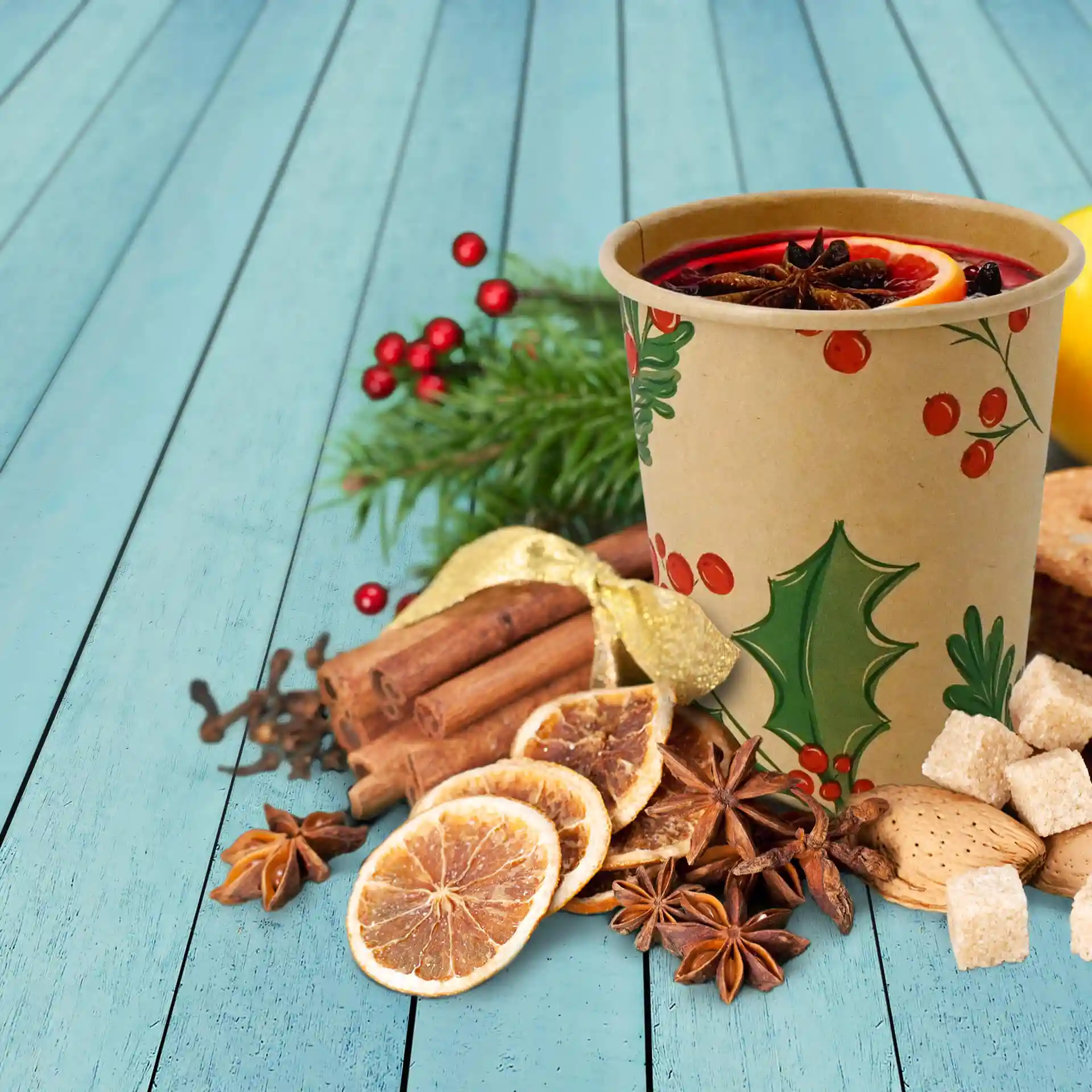 Brown paper cup with winter-themed design, surrounded by dried fruits, spices, and greenery on a blue wooden surface.