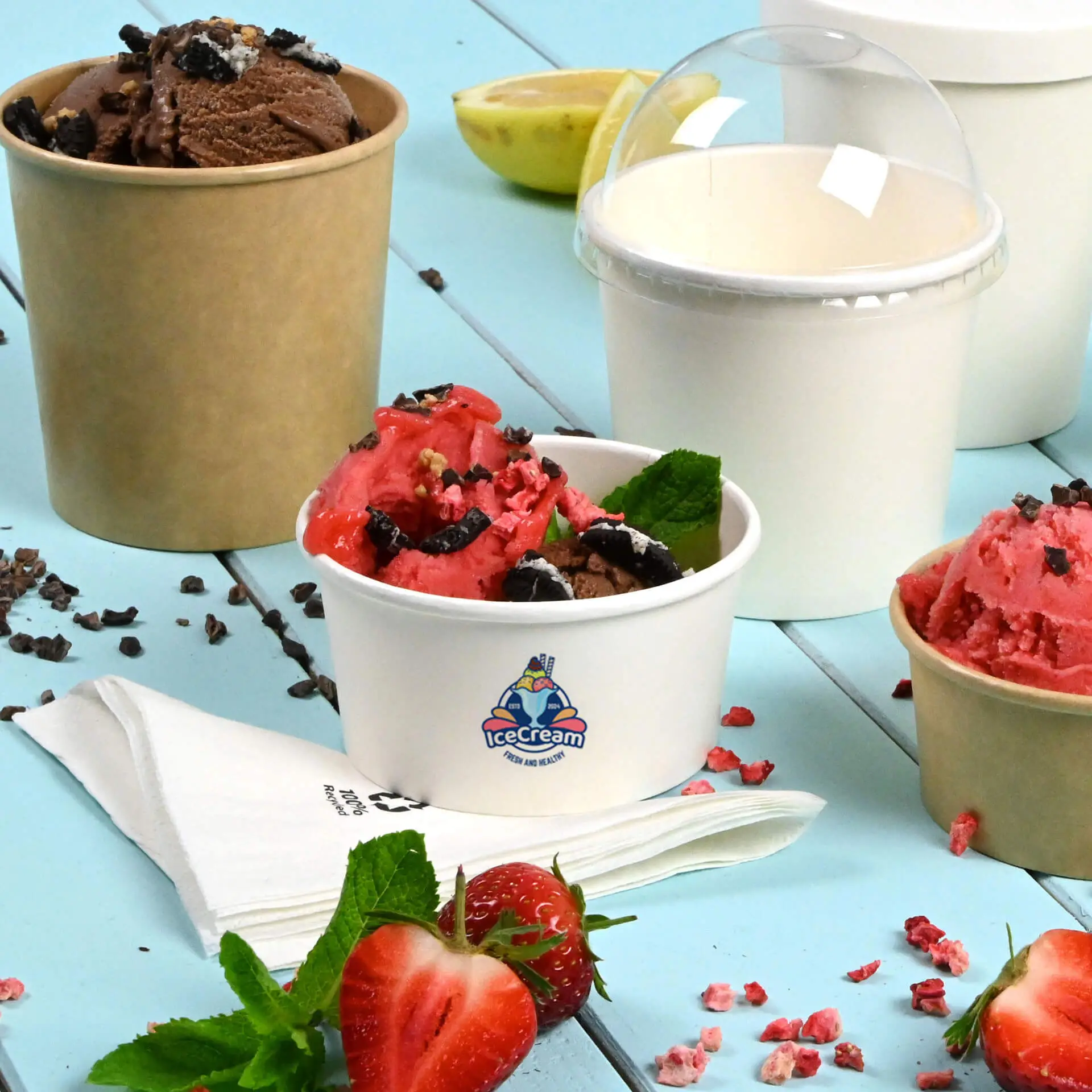Custom printed white ice cream cup with chocolate and strawberry ice cream; additional cups in the background; strawberries and mint leaves nearby.