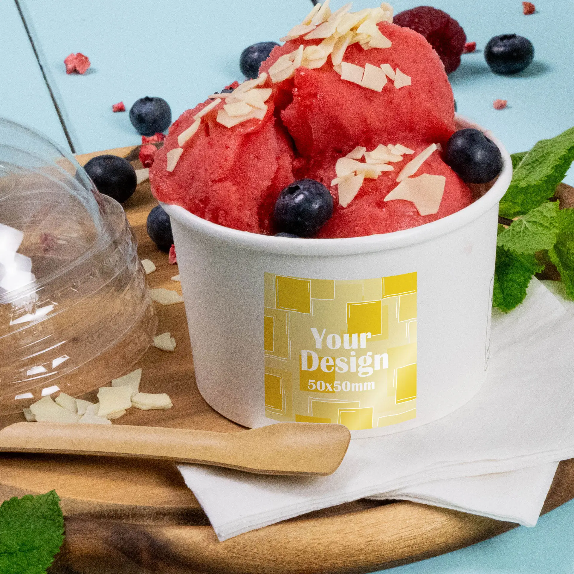 Cup of red sorbet topped with almond slivers and blueberries, displaying a custom printed label.