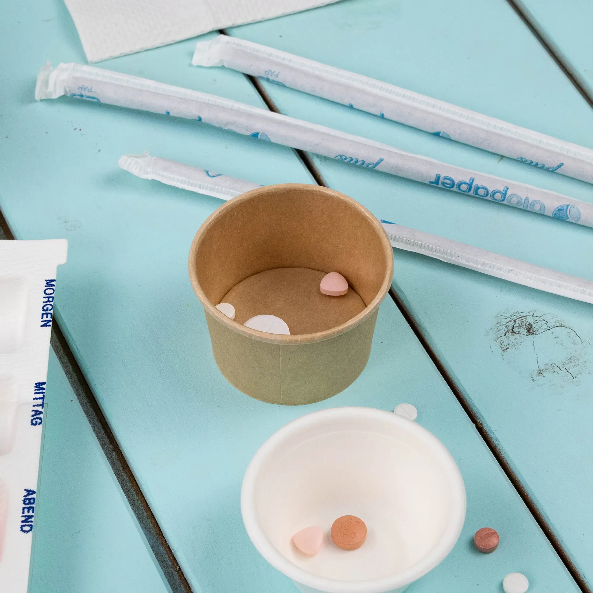 Deli container in brown, 40 ml, with small candies inside; white cup nearby with additional candies; paper straws in background.