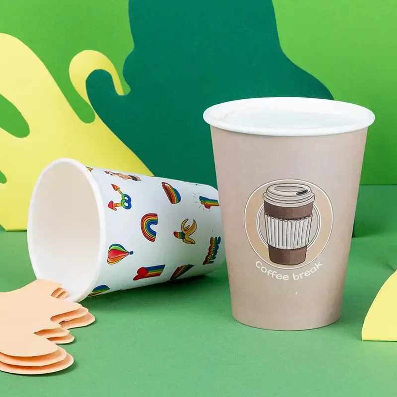 Double-walled pink paper cup with a custom design, topped with whipped cream and spices, resting on a blue surface.
