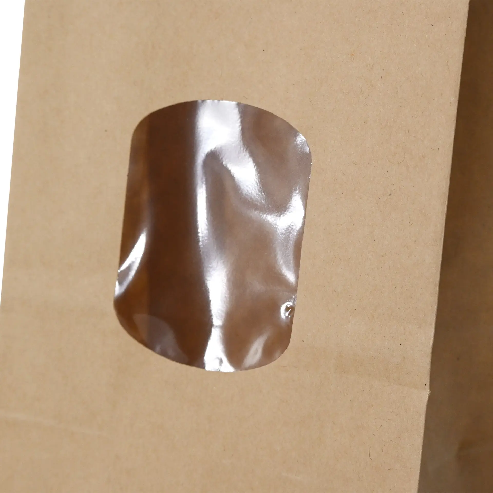 Brown kraft paper bag with a transparent PP-foil window, featuring a tin tie closure, measuring 8.5 x 5 x 24 cm.