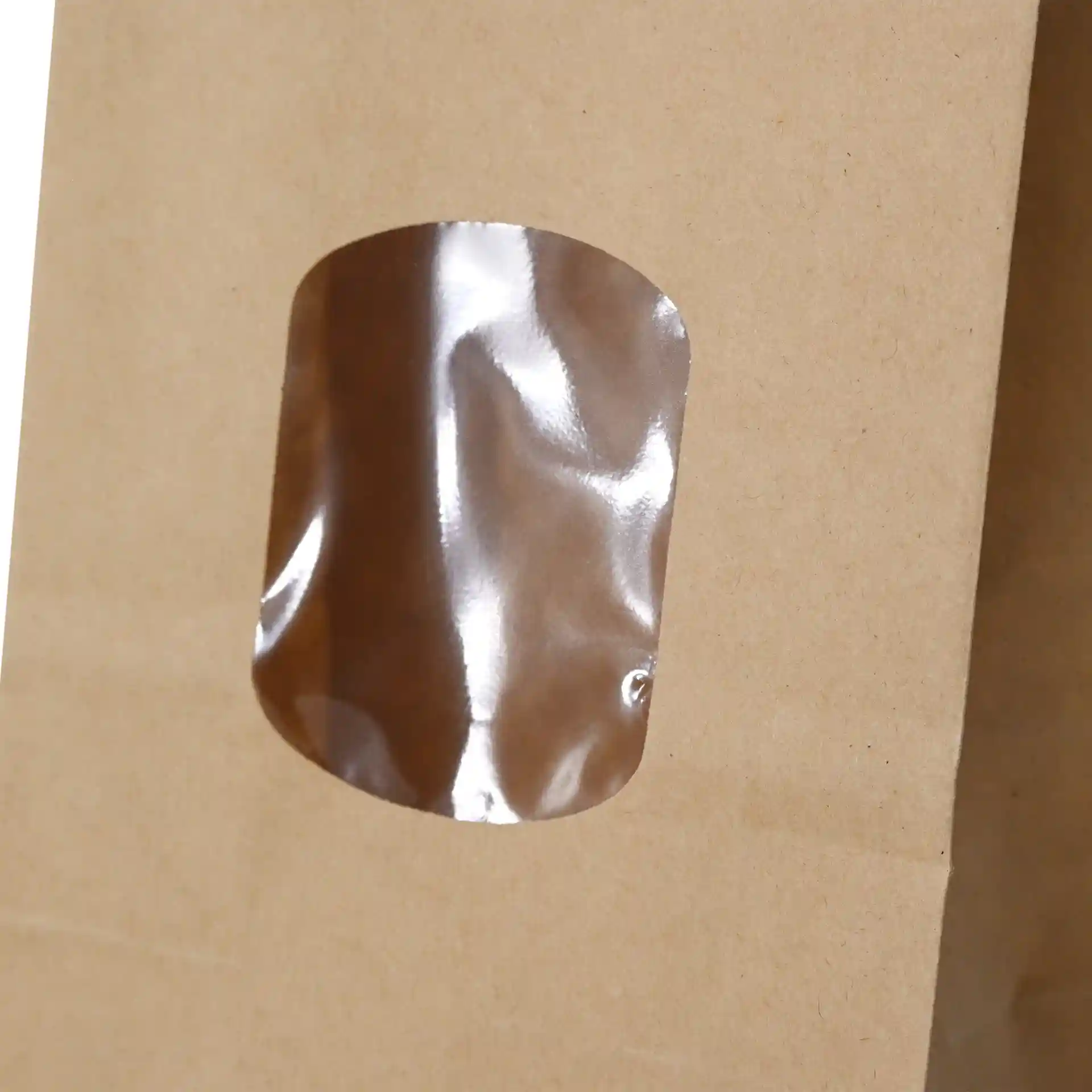 Brown kraft paper bag with a transparent PP-foil window, featuring a tin tie closure, measuring 8.5 x 5 x 24 cm.