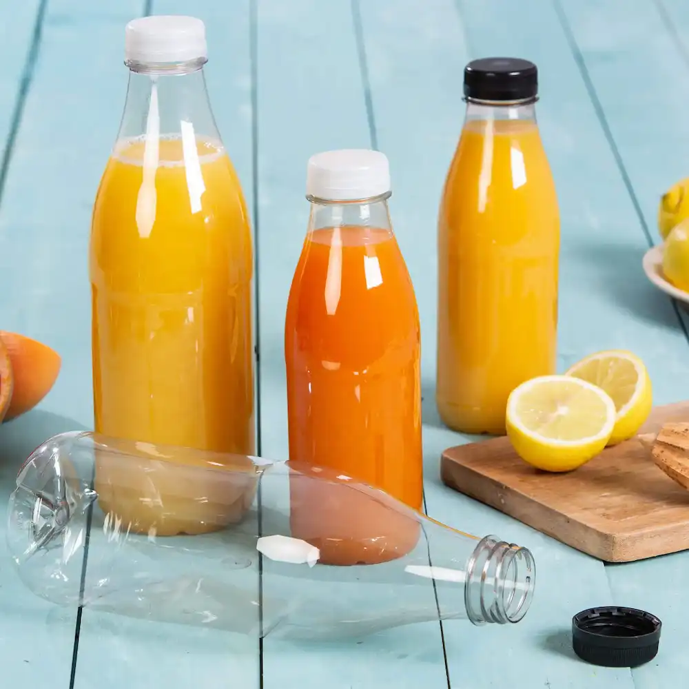 Three plastic bottles filled with yellow and orange juices, one bottle is lying down, and a lemon and cookies are nearby.