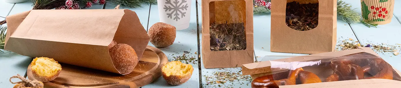Brown kraft paper bags with transparent windows; contains baked goods and herbs on a light blue surface with decorative elements.