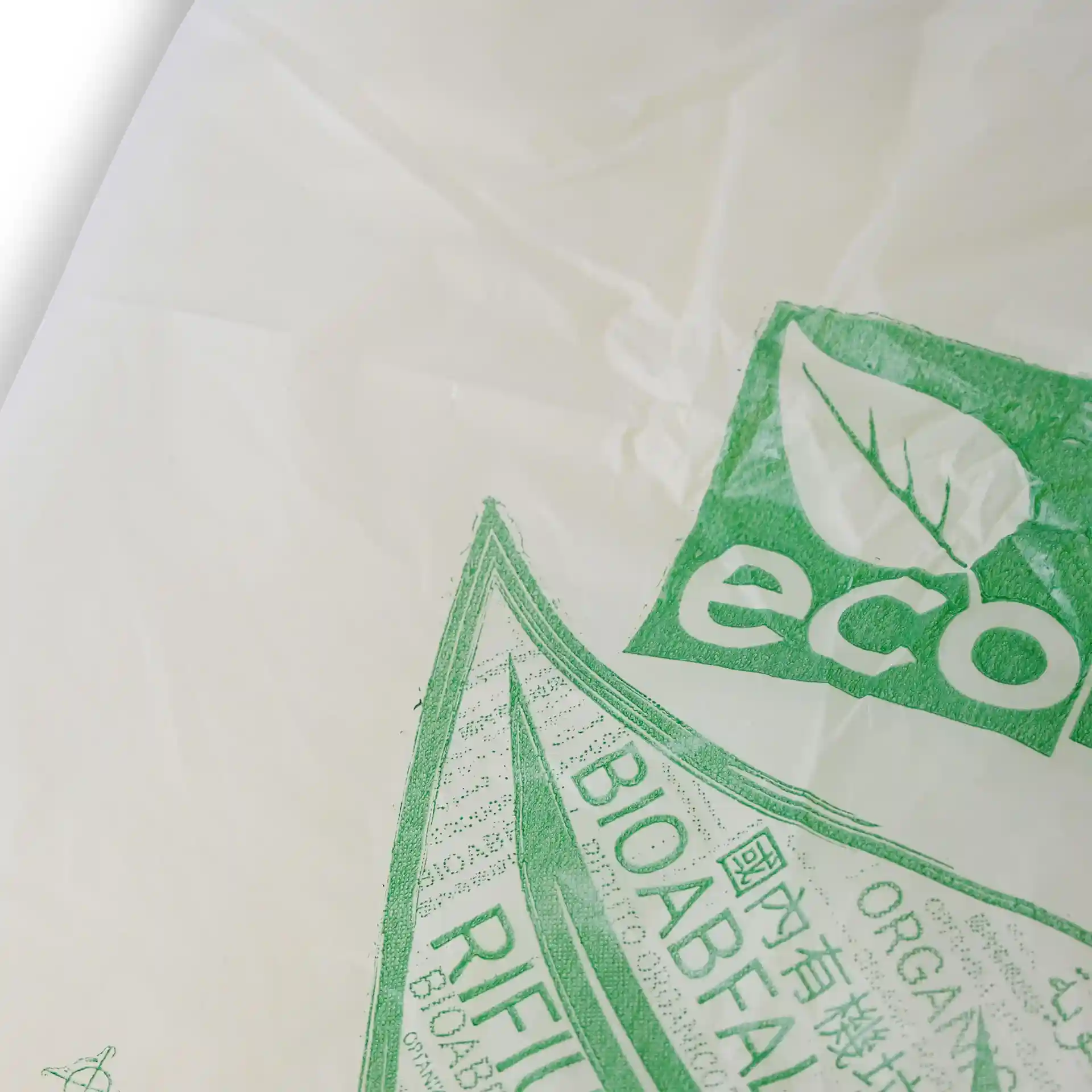 Transparent bio bin bag with green printed markings, including a leaf symbol and text indicating its bio-based material.