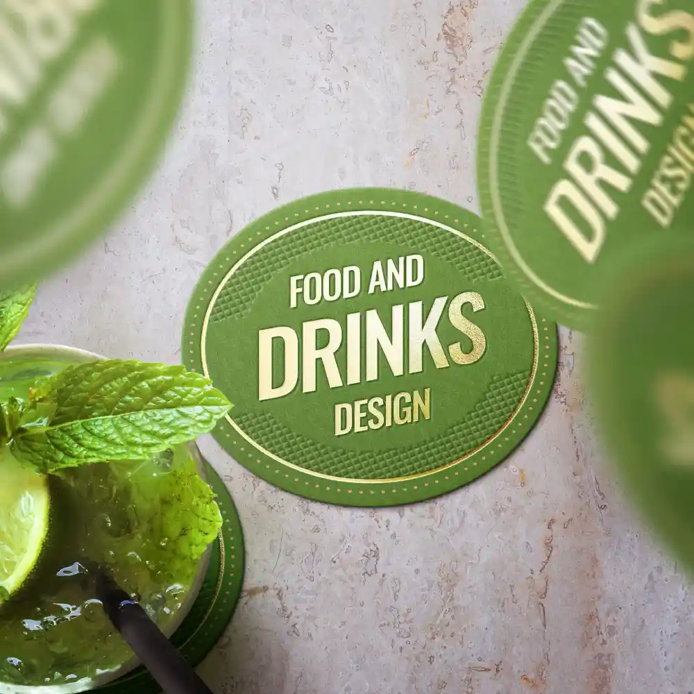 Green circular coaster with "Food and Drinks Design" text and a drink containing mint and lime in the foreground.
