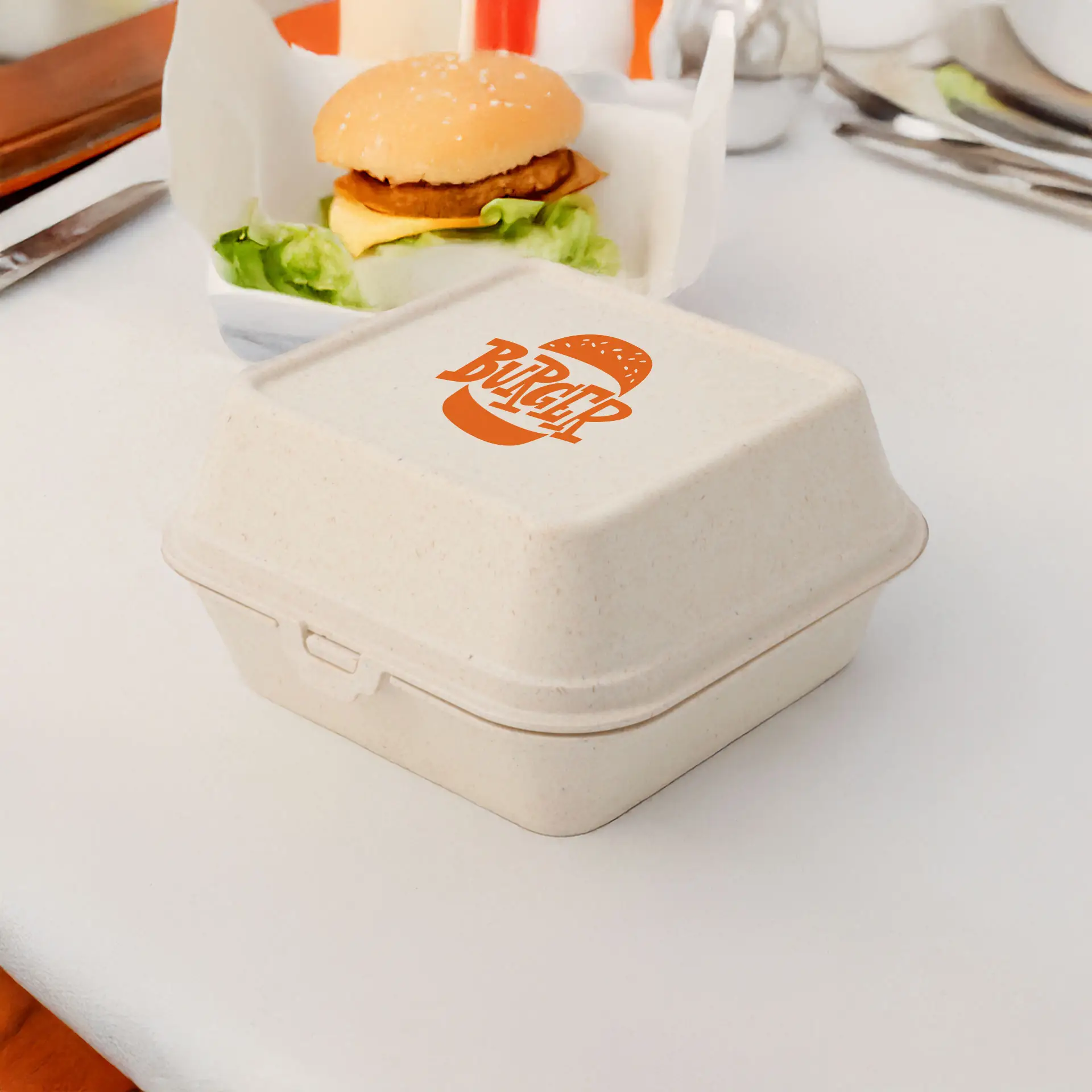 Cream white reusable burger box with a printed logo, suitable for hot and cold foods, placed beside a burger on a table.
