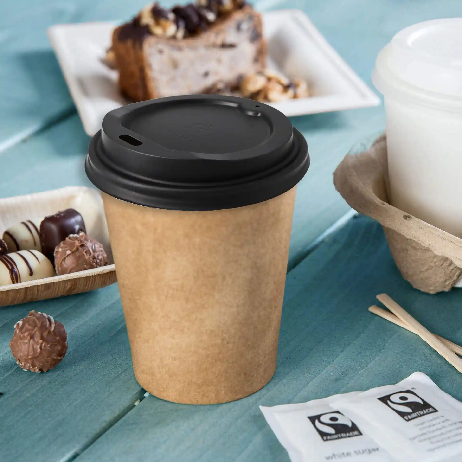 Black plastic lid with a drinking hole, designed for a 90 mm diameter cup, placed on a light brown paper cup.