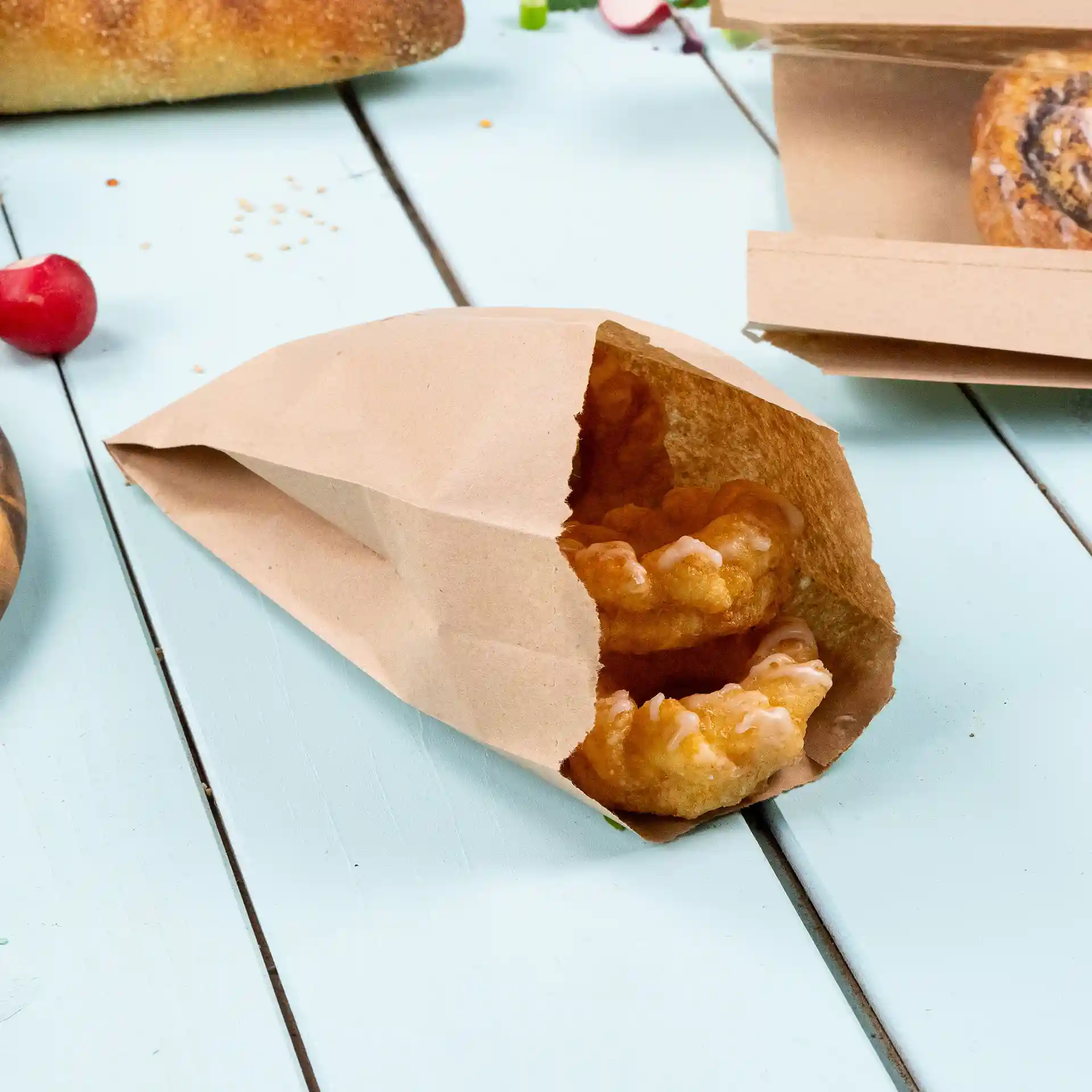 Brown flat paper bag containing two baked goods, placed on a light blue wooden surface.