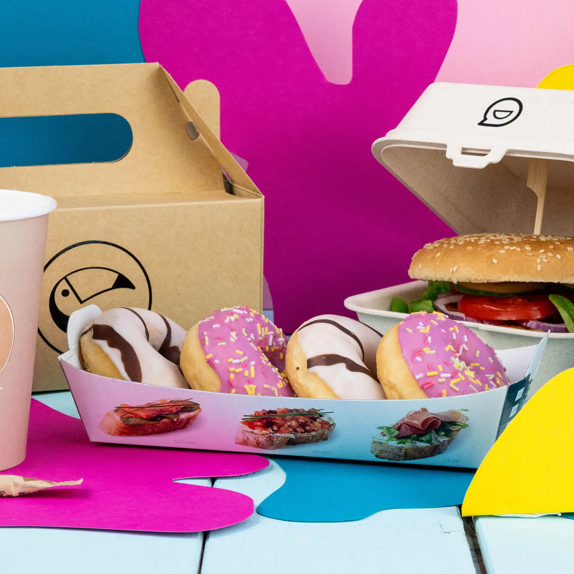 Rectangular white snack tray with four donuts, a burger in a container, and a pink cup on a colorful background.