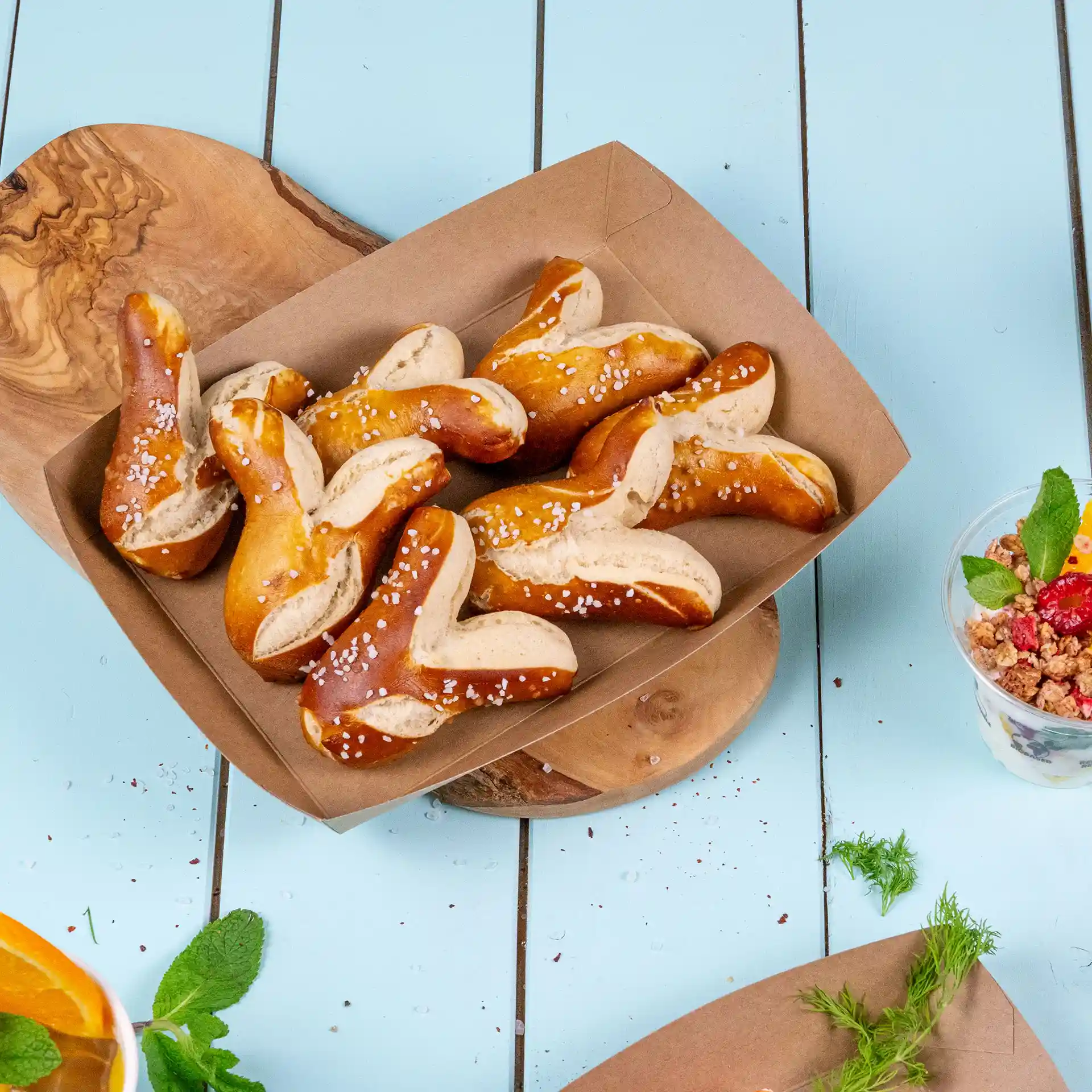 A brown cardboard food tray filled with several pretzel pieces topped with coarse salt.
