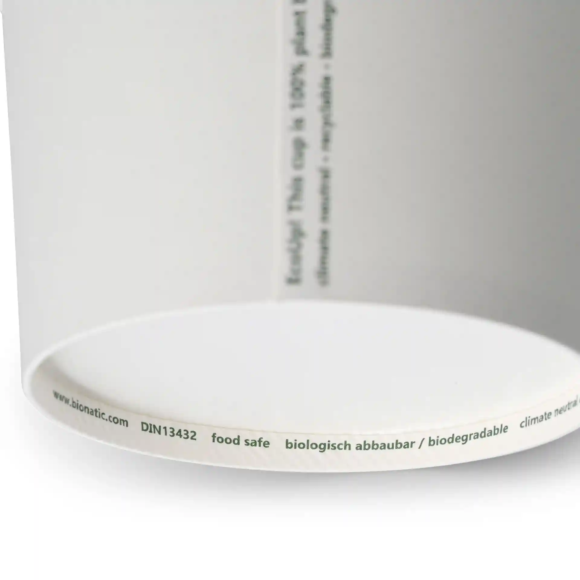 White paper soup container with a round shape, showing a label with markings on the bottom edge.