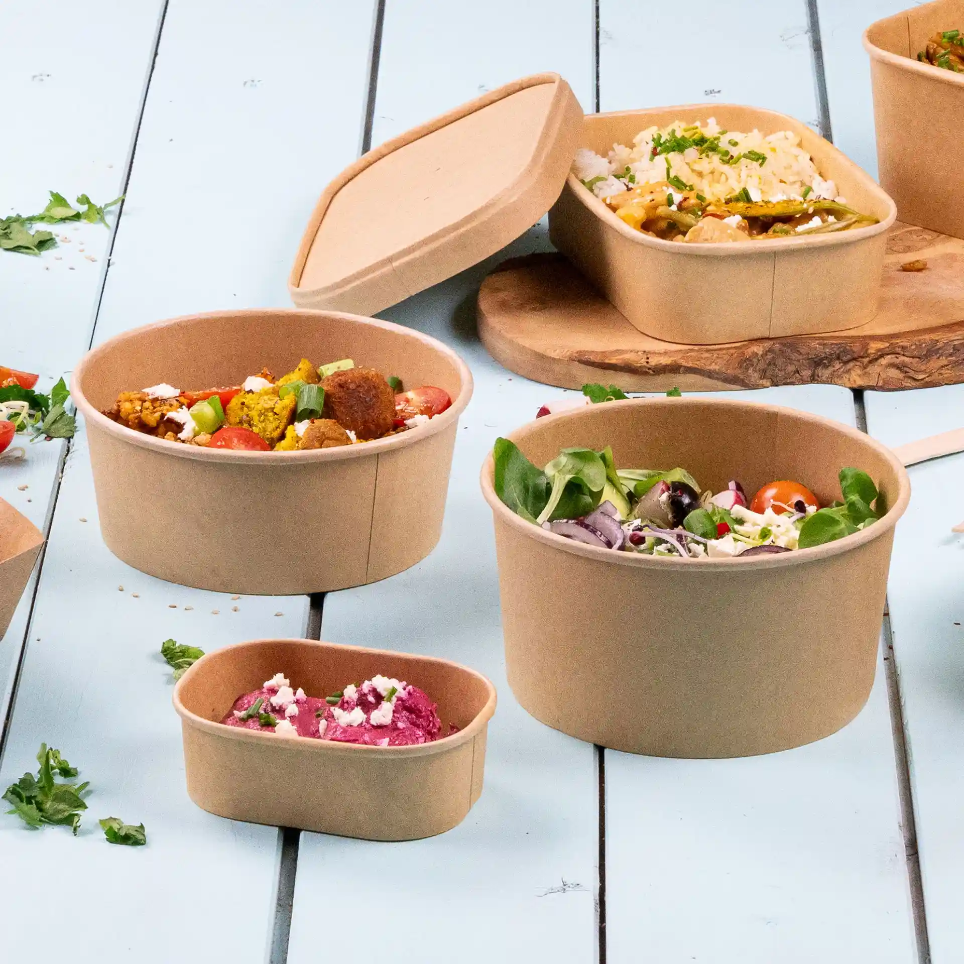 Image of several round brown paper bowls with lids, varying in size, placed on a light blue surface.