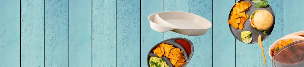 Green cartoon character beside a plate of nachos, salad, and a sandwich on a blue wooden background.